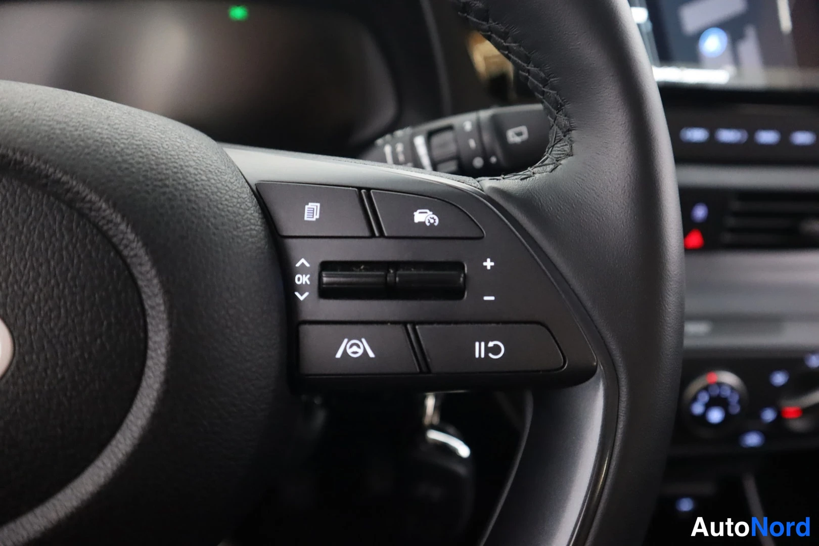 Yksityiskohta: Ohjausrattin vasemmanpuoleisen hallintapainikesarjan lääkakuva: painikkeet tiedusteluun/ruutuun ylöspäin, alas, OK, + ja -, Cruise Control -valitsin (c) ja pysä