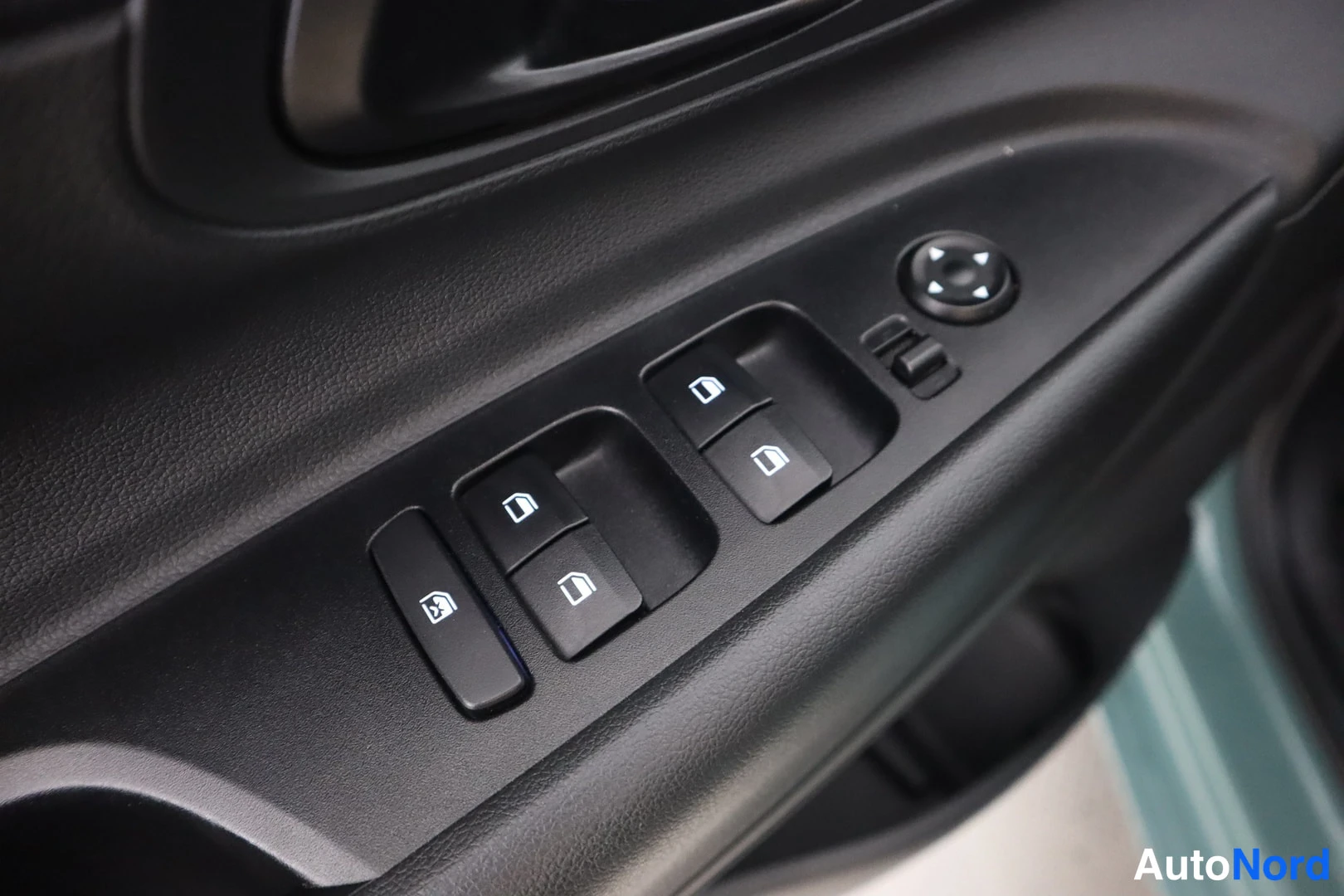 Yksityiskohta: Close-up of the driver's door control panel featuring four window lift switches and a side mirror adjustment joystick.