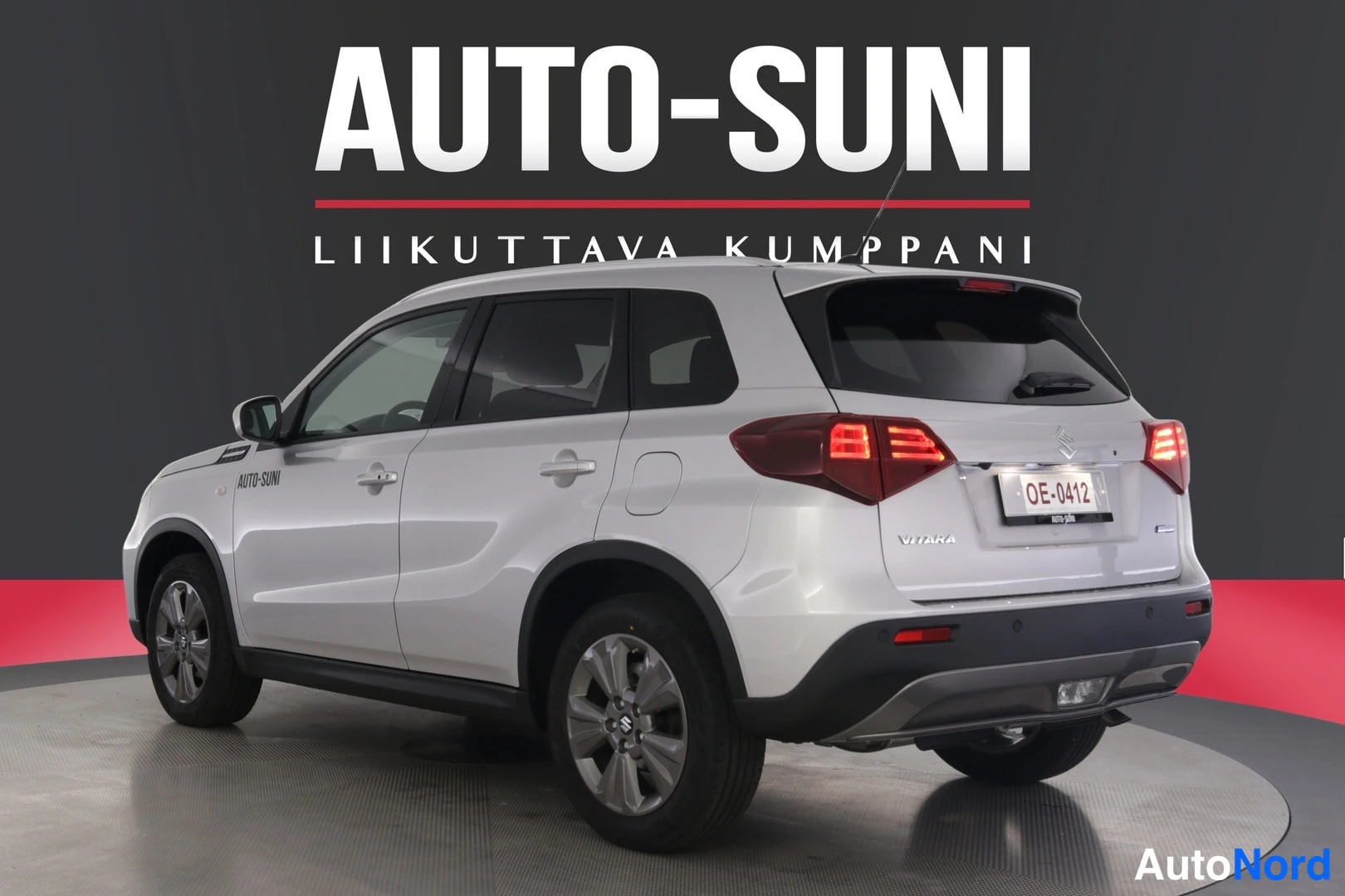 Takaviisto: Takana ja oikealta otettu kuva valkoisesta SUV-kirja-autoista. Näkyvissä ovat takavalot, 'VITARA'-merkki ja vasen sivu.