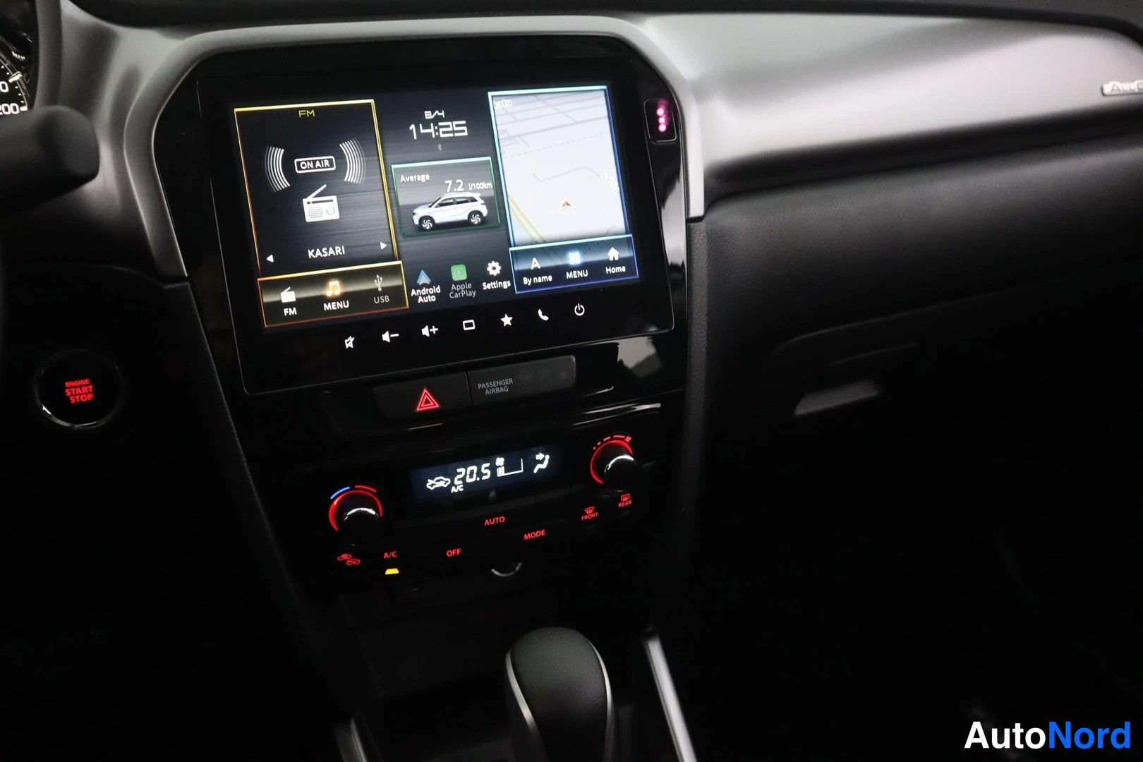 Muu: Suzuki Vitaran keskikonsolin kosketusnäyttö radiokanavalla ja navigointikartalla, alla digitaalinen ilmastointipaneeli.