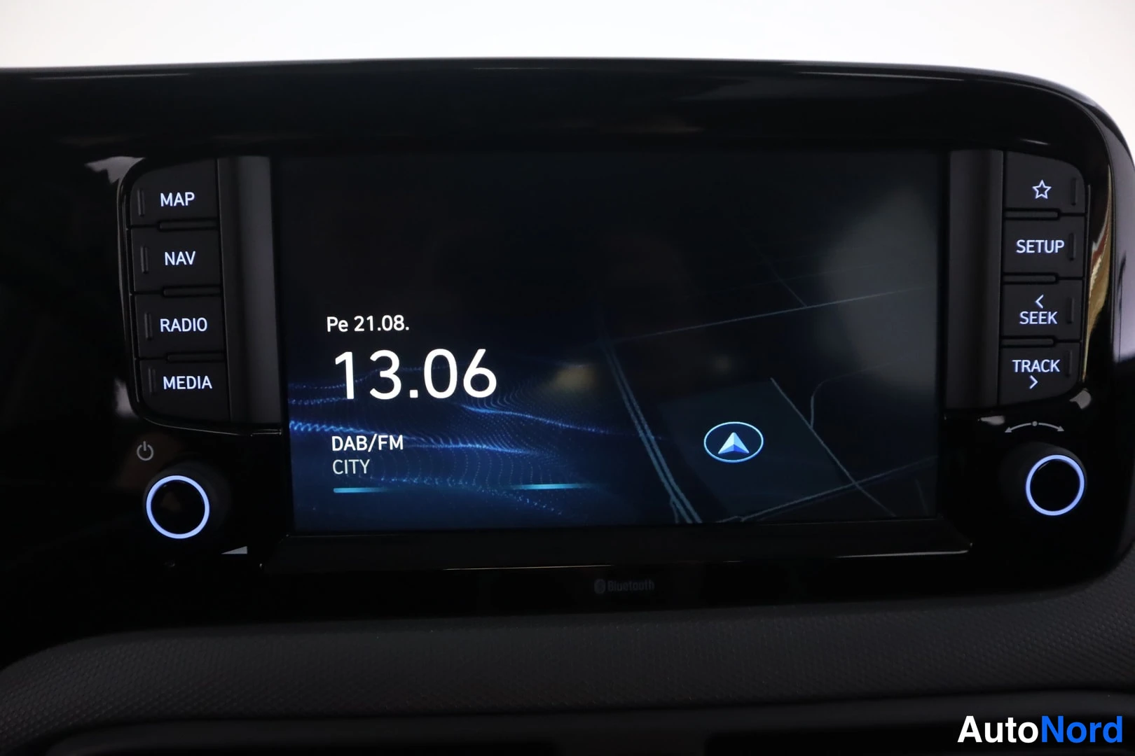 Ohjaamo: Infotainment-näyttö keski-illalla: kellonaika 13.06, päivämäärä Pe 21.08., radiotila DAB/FM CITY, ruudulla nuoli navigointiosoitteena, näytön alareunassa Blueto