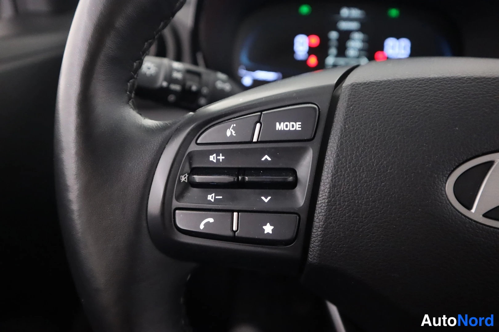 Etuistuimet: Close-up of the steering wheel showing multifunction controls including buttons for MODE, volume adjustment, track selection, a phone call button, and a favorit