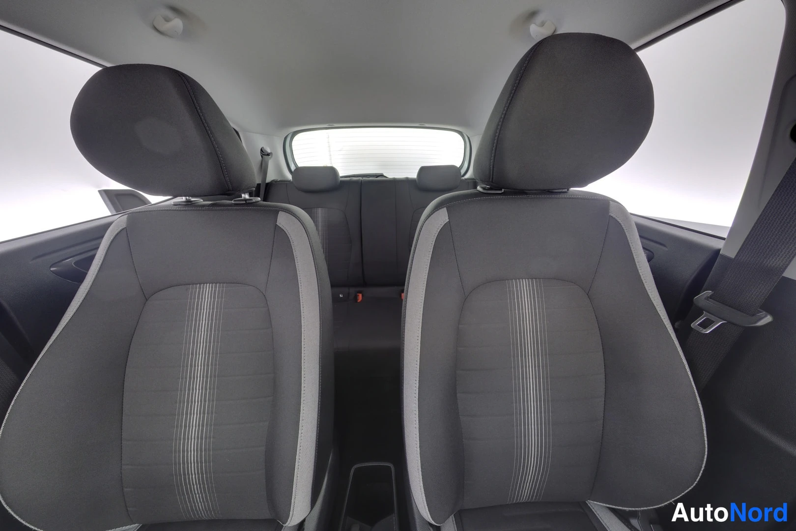 Takaistuimet: View from the front seats looking back into the cabin, showing the backs of the two front seats and the rear bench seat. Three headrests are visible for the rea