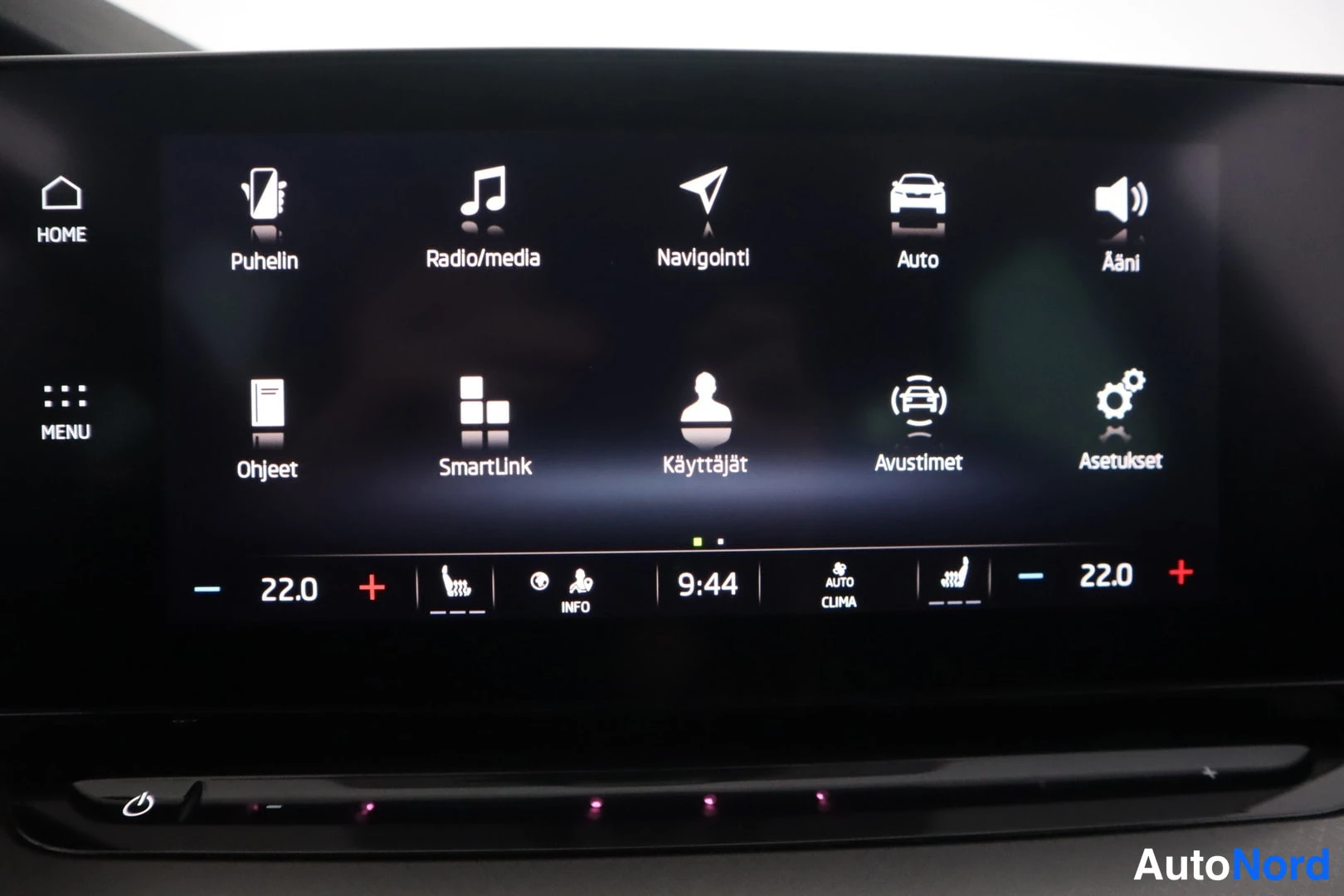 Yksityiskohta: Infotainment-näytön päävalikko kuvattuna läheltä. Ruudulla ovat kohdat Puhelin, Radio/media, Navigointi, Auto, Ääni, Ohjeet, SmartLink, Käyttäjät, Avustimet ja