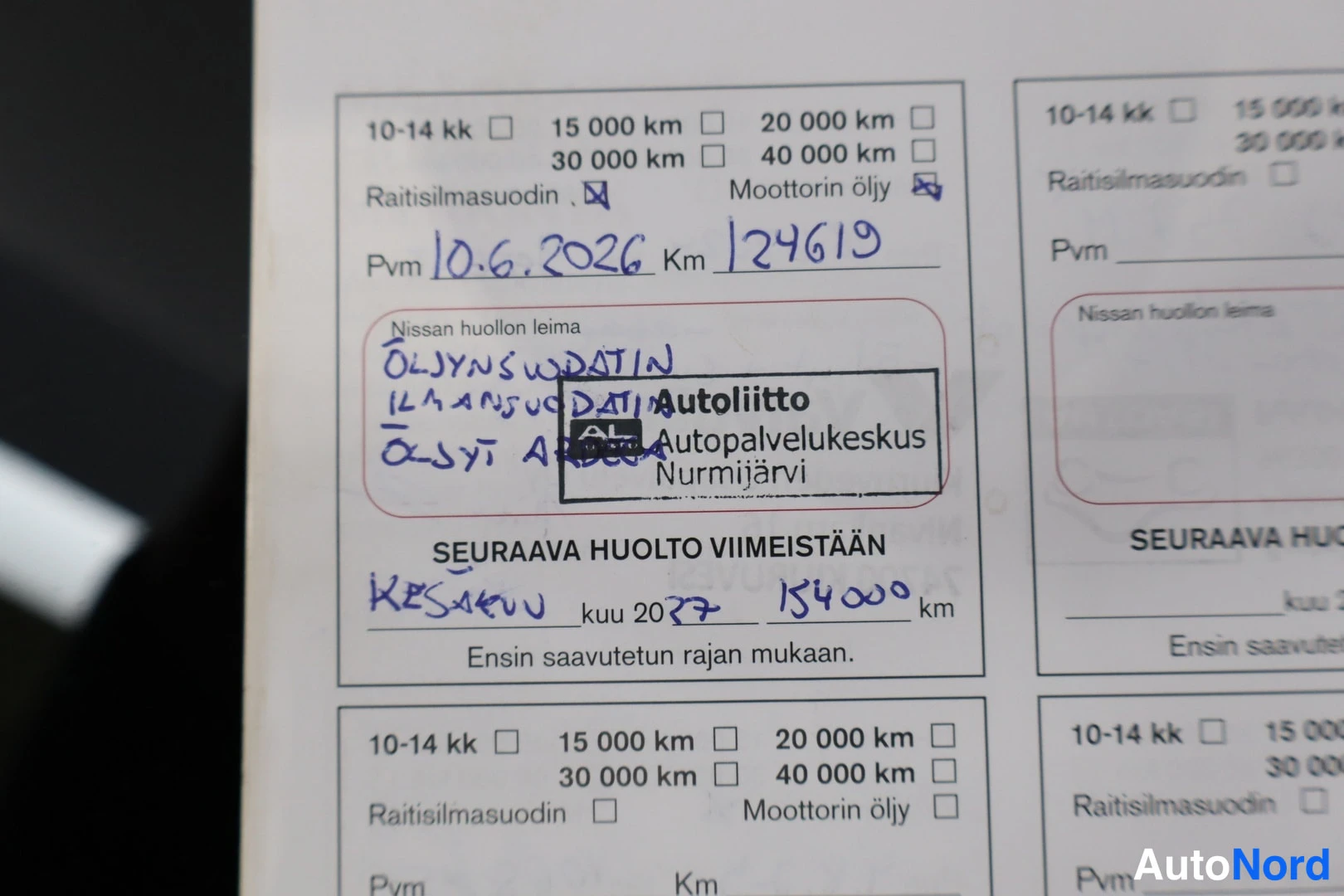 Muu: Nissanin huoltoleimapassista lähikuva: käsinkirjoitettu huolto 10.6.2026, km 124619, leima Autoliitto Autopalvelukeskus Nurmijärvi.