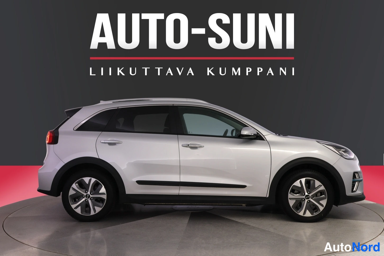 Sivulta: Kia Niro e-SUV sivusta vasemmalta, hopeinen koriratkaisu, kevytmetallivanteet ja kattokaiteet.