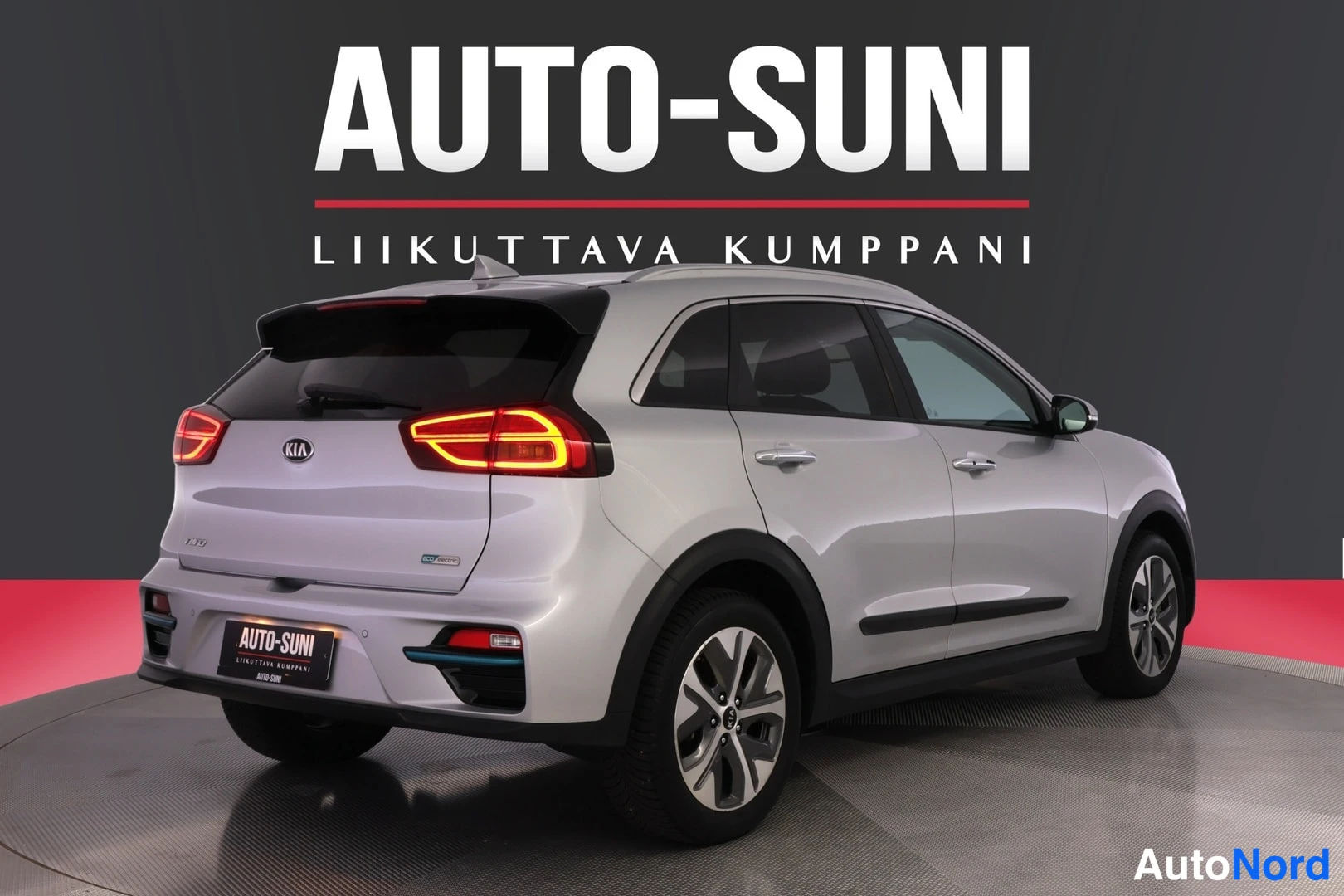 Takaviisto: Kia Niro e-SUV takaviisto vasemmalta, hopeinen koriratkaisu, LED-takavalot ja Auto-Suni-kyltti.