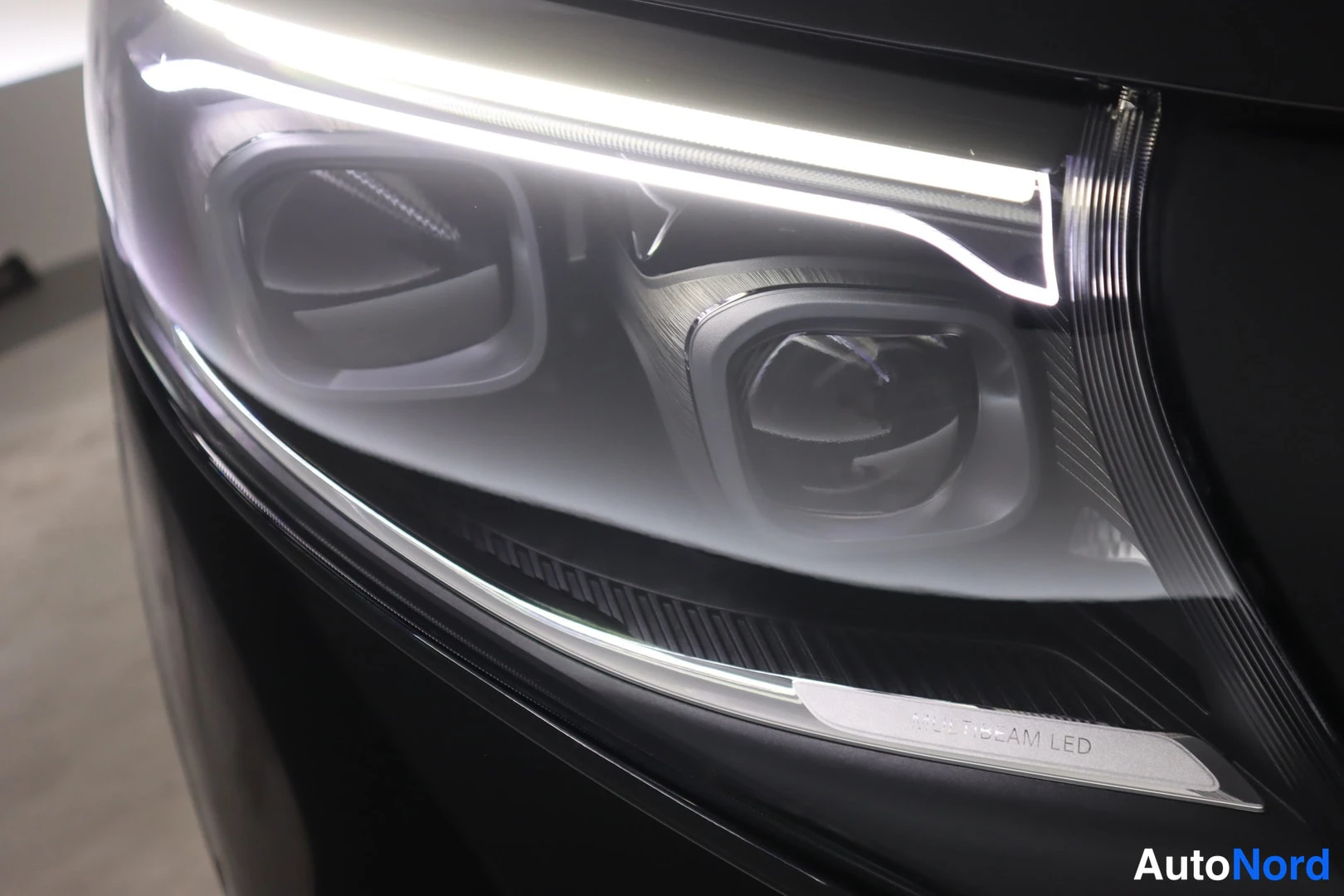 Yksityiskohta: Mustan auton etuvalaisimen lähikuva, DRL-kaarivalo ja teksti MULTIBEAM LED lasissa.