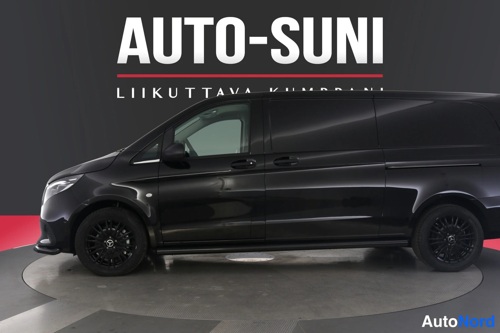 Sivulta: Musta Mercedes-Benz Vito -pakettiauto sivulta-etviistosta, keula vasemmalla, Auto-Suni-hallissa.