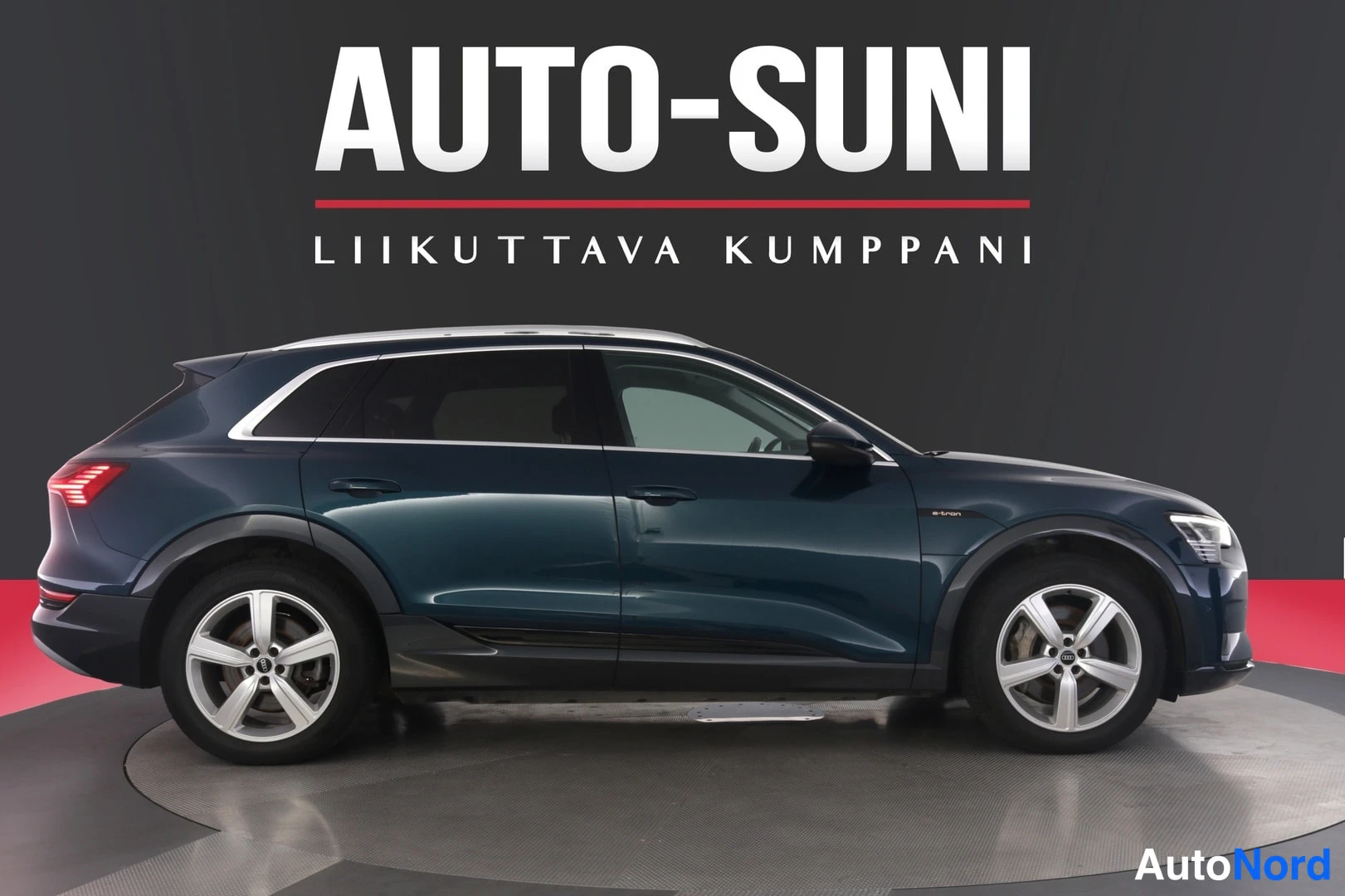 Sivulta: Tummansinisen Audi e-tron -maasturin sivukuva studioseudilla.