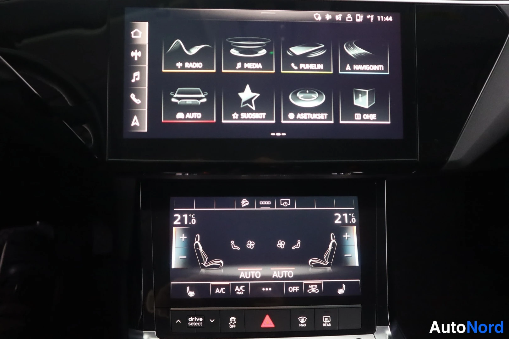 Muu: Audi e-tronin keskinäyttö ja alempi ilmastointinäyttö: valikot RADIO, MEDIA, PUHELIN, NAVIGOINTI; molempien puolia lämpötila 21,5 °C.