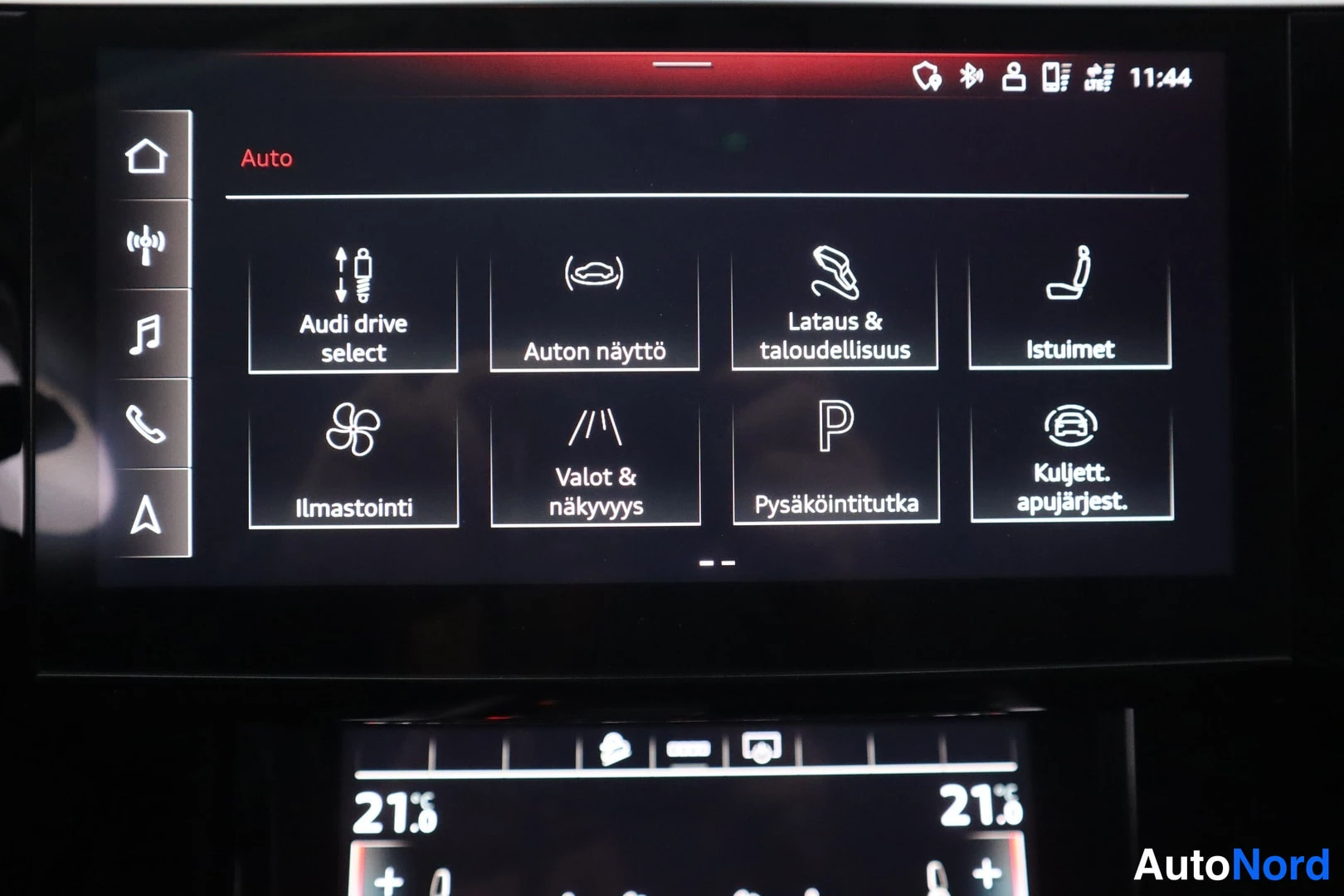 Yksityiskohta: Auton keskikäyttöpaneelin näyttö, jossa Auto-valikko ja kuvakkeet kuten Audi drive select, Lataus & taloudellisuus ja Ilmastointi.