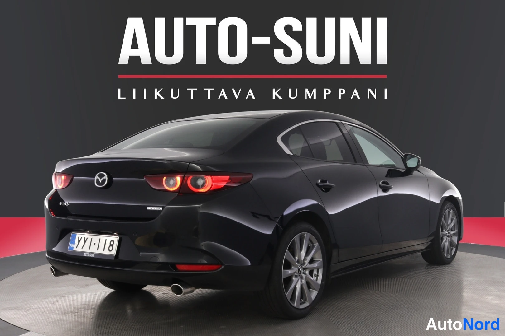 Takaviisto: Musta Mazda3-sedan taka­os­a ja oikea sivu, rek­k­eri­, kau­sa­val­ot ja pak­sa­pa­le nä­ky­vis­sä.
