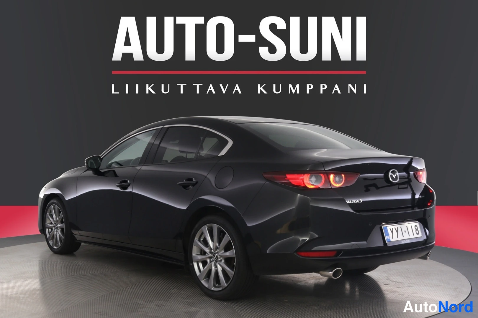 Takaviisto: Musta Mazda3-sedan taka­os­a ja vasen sivu, rek­k­eri­, MAZDA3-mer­k­in­nä boot-li­dil­lä.