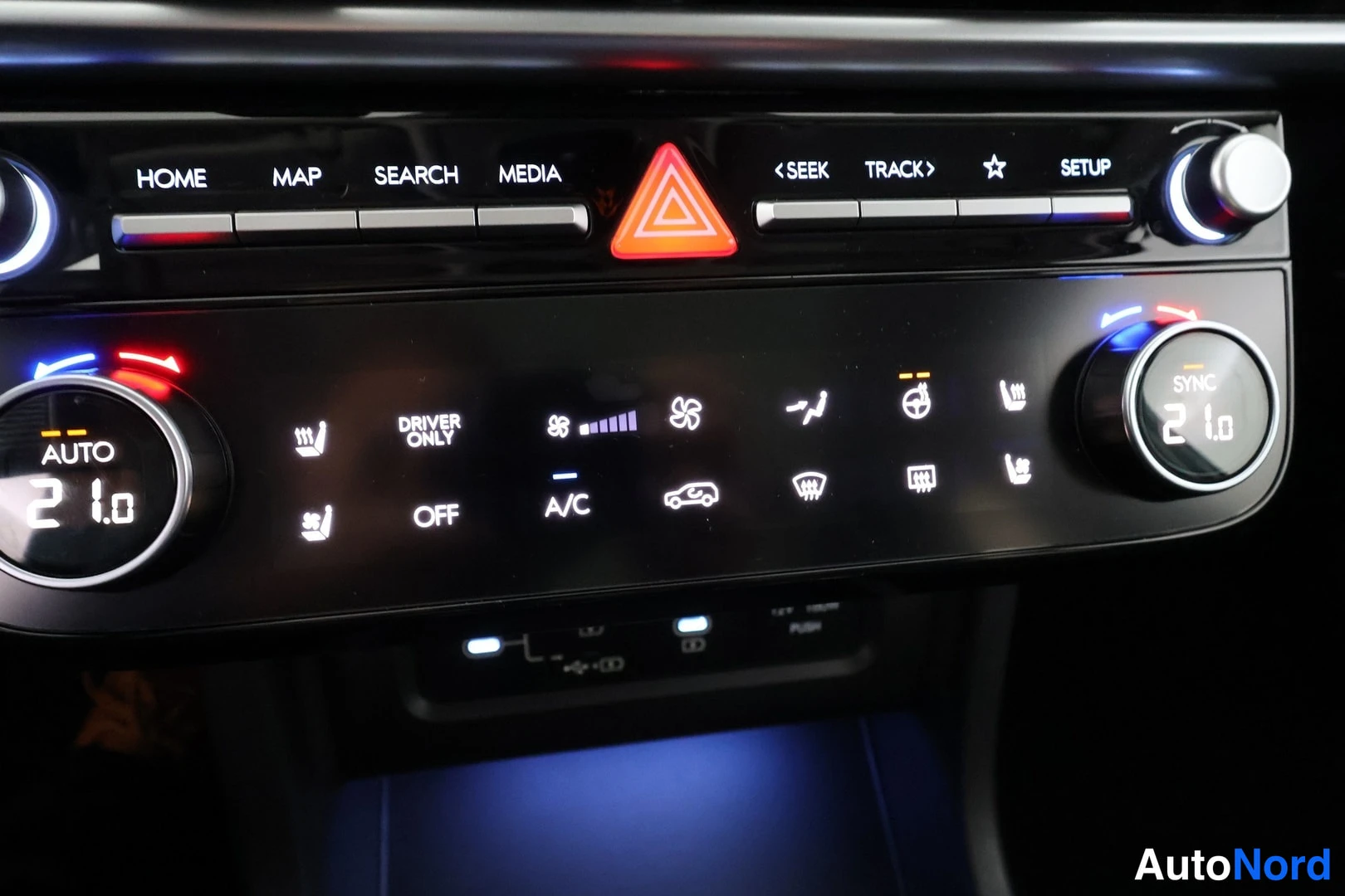 Muu: Keskiöconsolen lämpötila- ja mediapaneeli: AUTO-napit 21,0 °C molemmin puolin, SYNC, A/C, OFF, DRIVER ONLY ja istuinlämpötilan merkit.