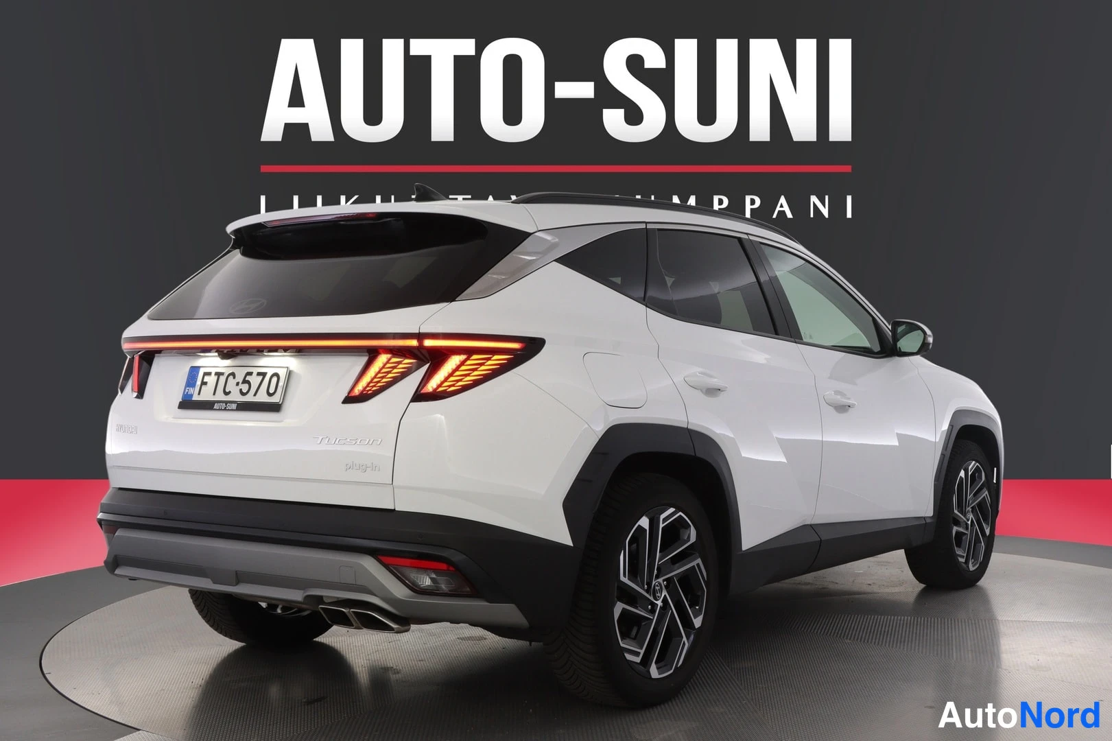 Takaviisto: Hyundai Tucson, valkoinen auto takakulmasta kuvattuna, näkyvät takavalot, aukko ja rekisterikilpi, studiotausta