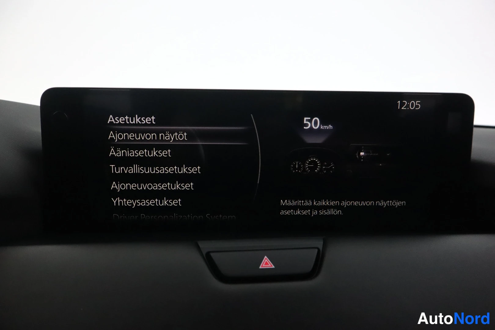 Muu: Auton infotainment-näyttö asetusvalikossa, jossa näkyy mm. kello 12:05.