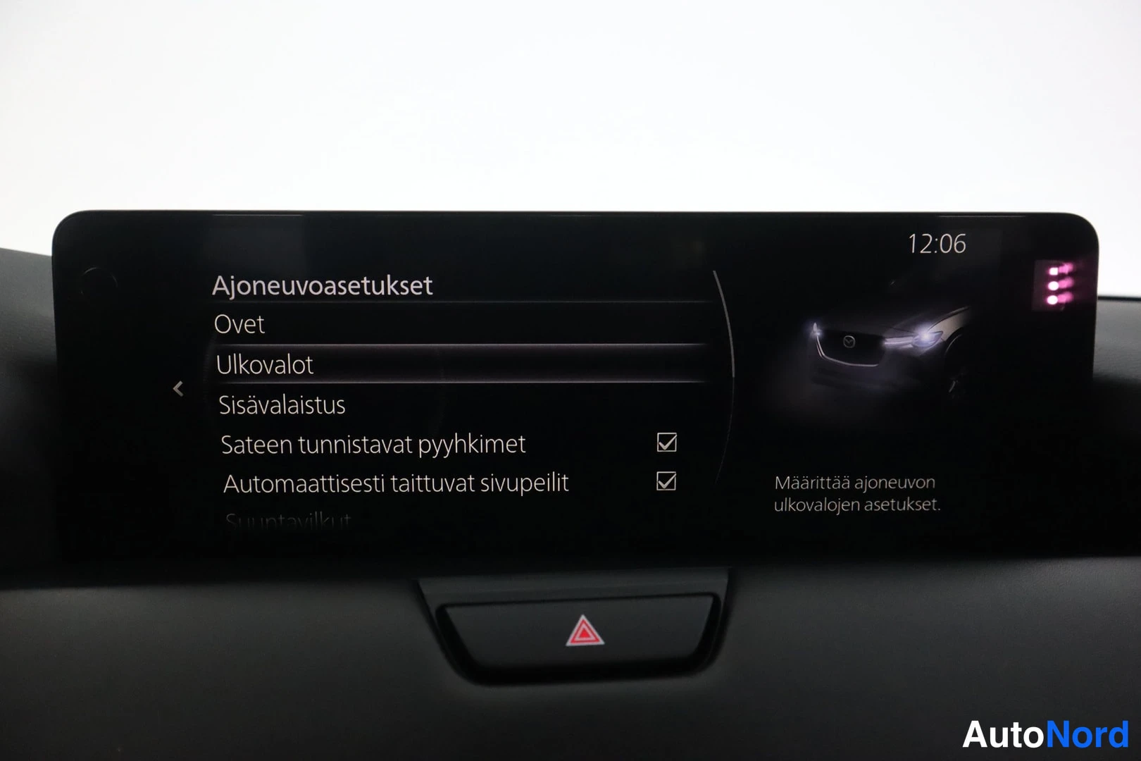 Muu: Auton kojelaudan infotainment-näyttö, jossa auki Ajoneuvoasetukset-valikko ja varoitusvalon painike alla.