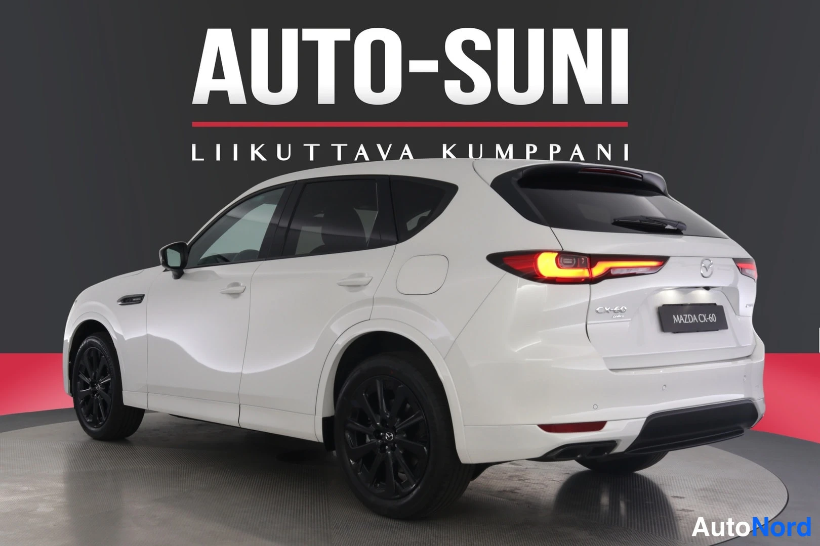 Takaviisto: Valkoisen Mazda CX-60:n takakulma toisesta suunnasta, takavalot ja musta takapuskuri näkyvissä.