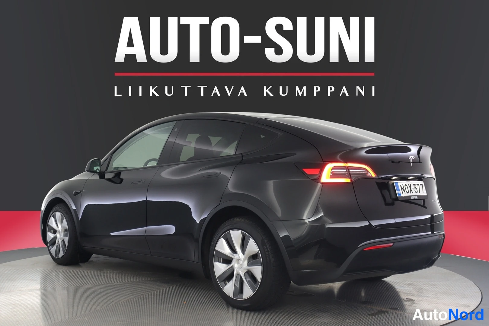 Takaviisto: Musta Tesla Model Y takaosa ja vasen kylki näkyvät kulmasta, rekisteritunnus.