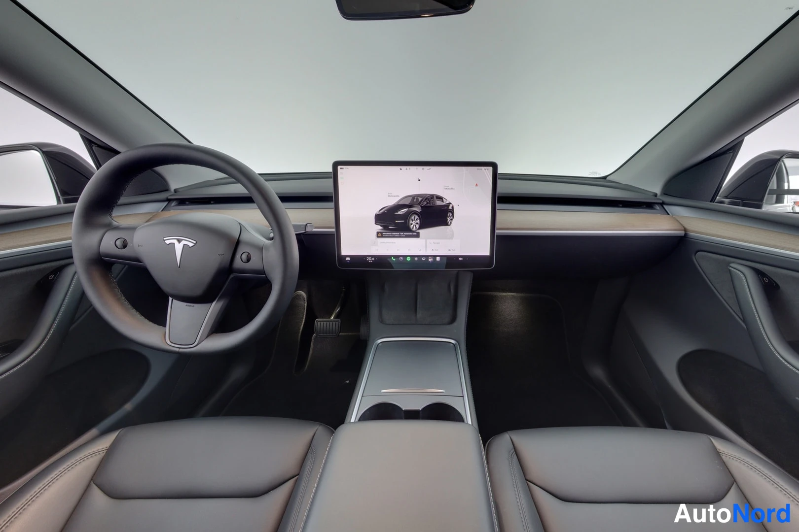 Etuviisto, nokka vasemmalle: Auton ohjaamo edestä: Tesla-logollinen ohjauspyörä ja keskikonsolin suuri kosketusnäyttö.