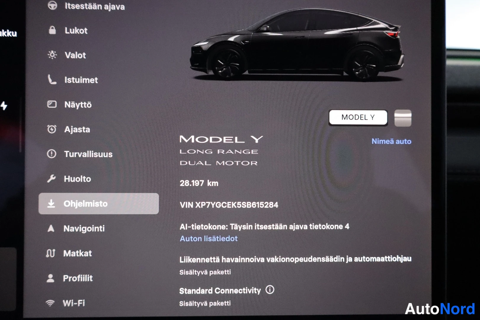 Muu: Kojelaudan infotainment-näyttö, jossa on suomenkielinen valikko ja ajoneuvon tiedot: Model Y Long Range Dual Motor, 28 197 km ja VIN-tunnus.