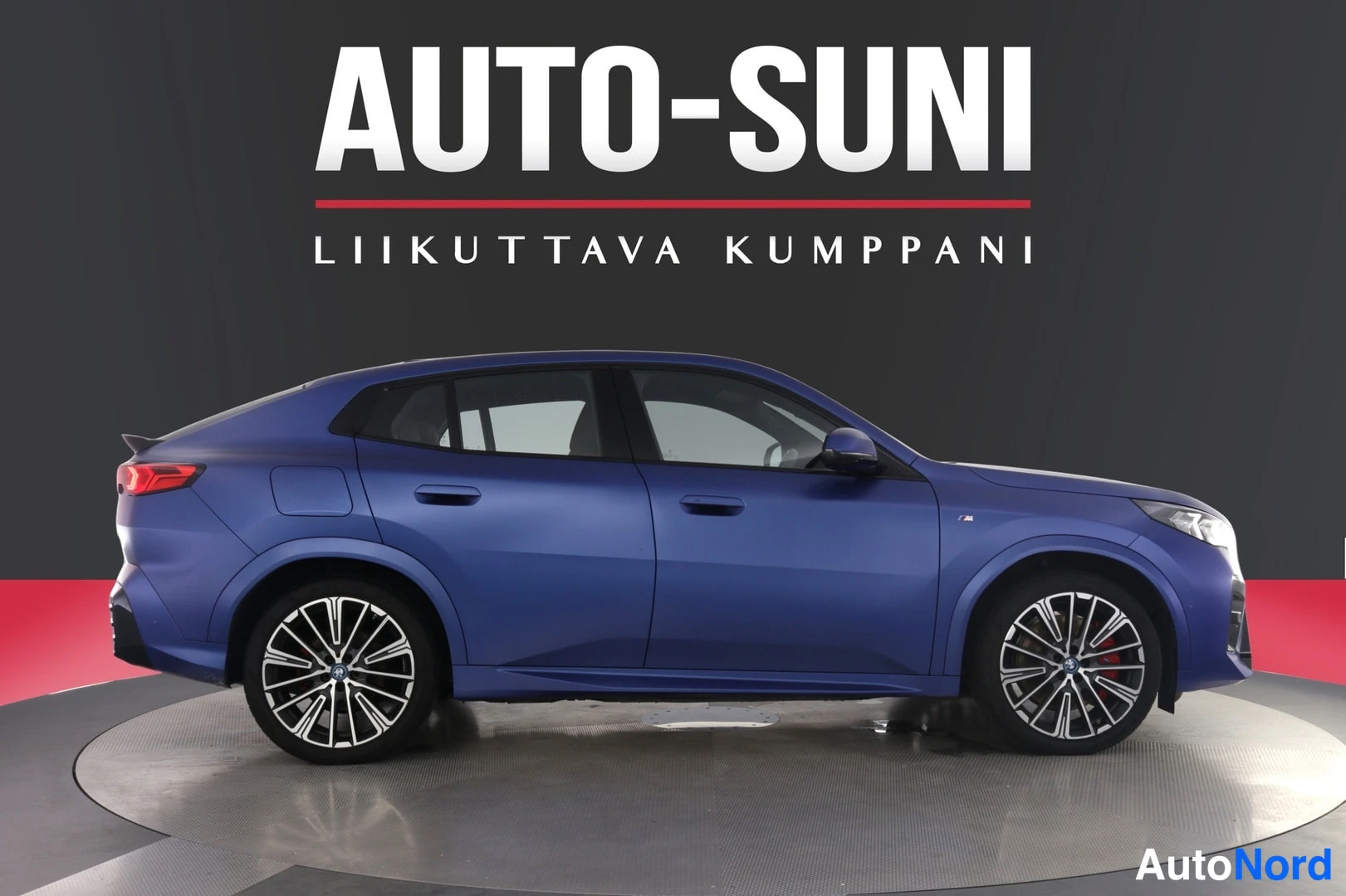 Sivulta: Sininen BMW X2-sivuprofiili studio-taustaa vasten.