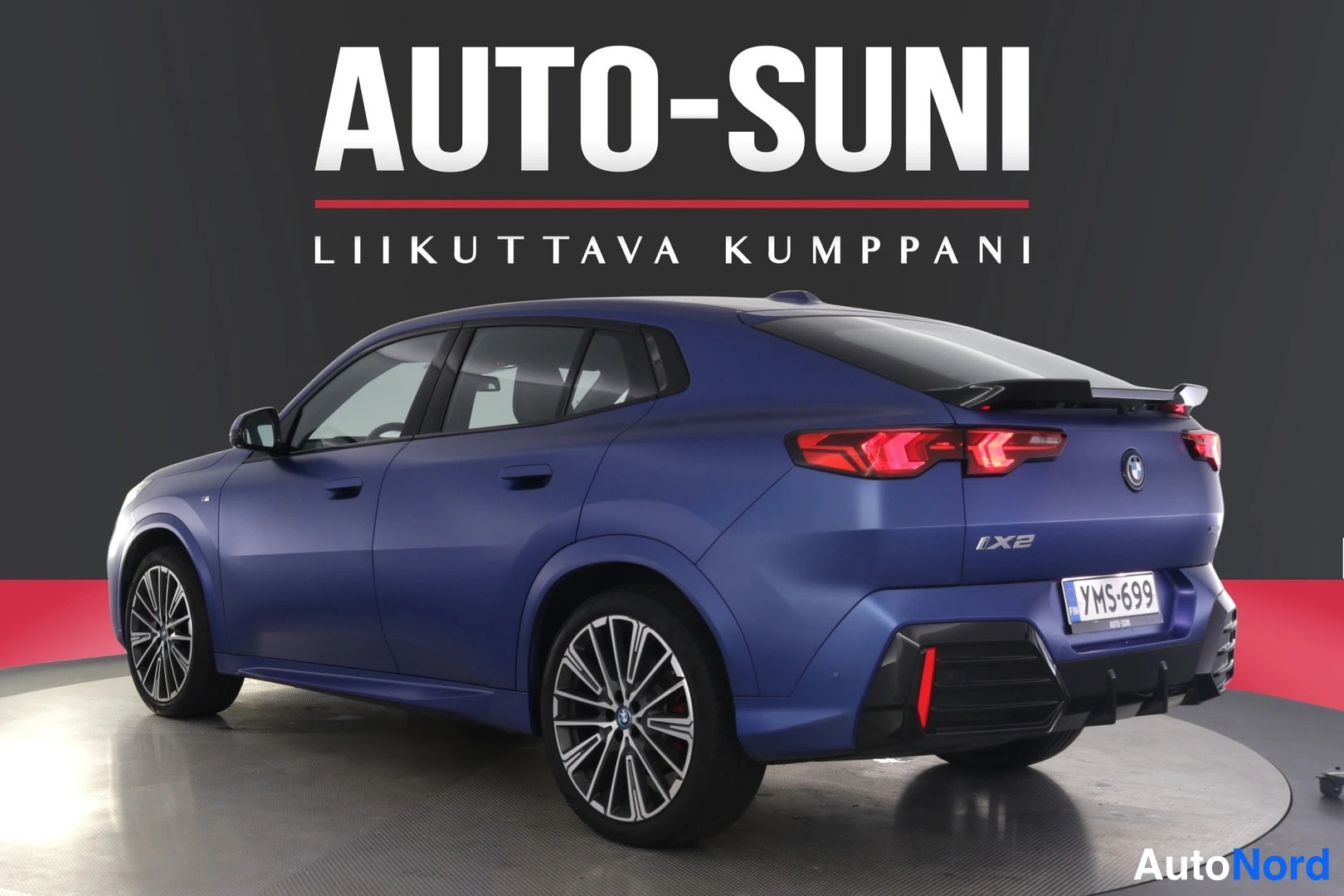 Takaviisto: Sininen BMW iX2-takakolmasosa toisesta kulmasta, iX2-merkintä ja rekisteritunnus.