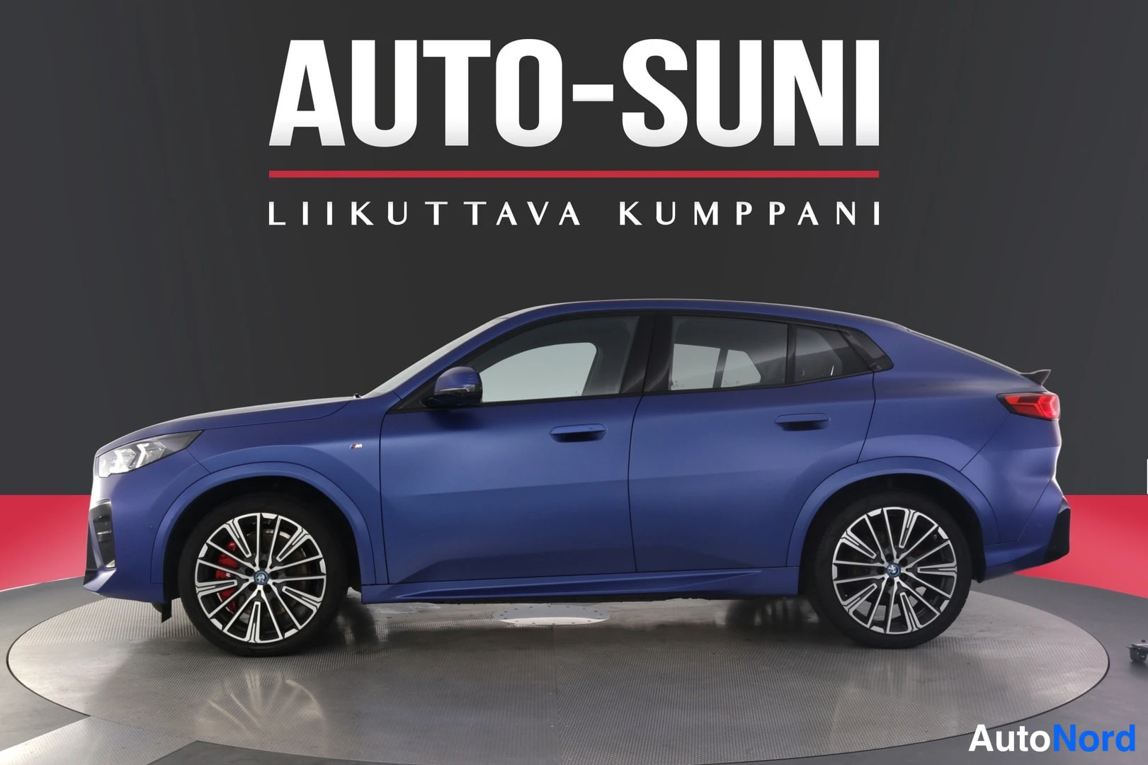 Sivulta: Sivukuva sinisestä BMW X2 Coupé -tyylisestä autosta studiossa, koko auto näkyvissä.