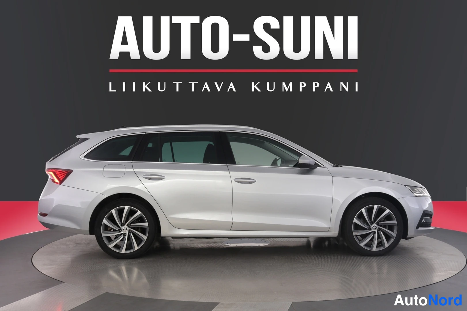 Sivulta: Sivukuva hopeanvärisestä farmariautosta studiossa; kuljettajan puolen ovet ja pyörät näkyvissä.