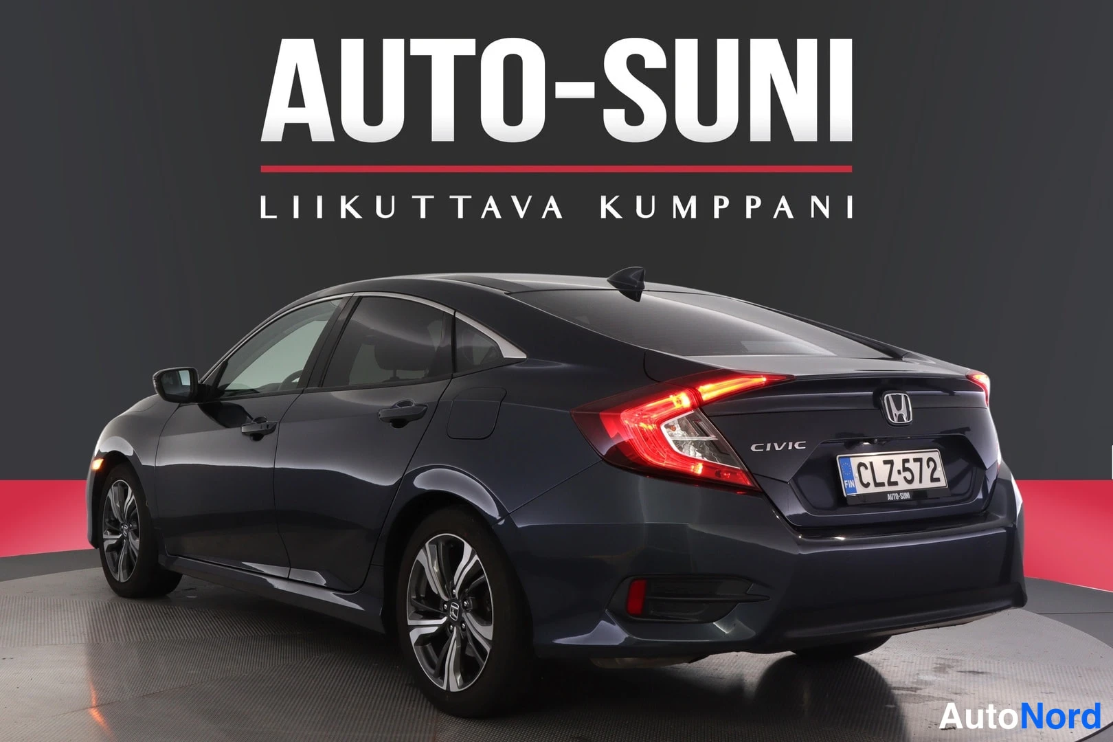 Takaviisto: Honda Civic -sedanin takakulma toisesta suunnasta, tummansininen koripinta, rekisterikilpi.