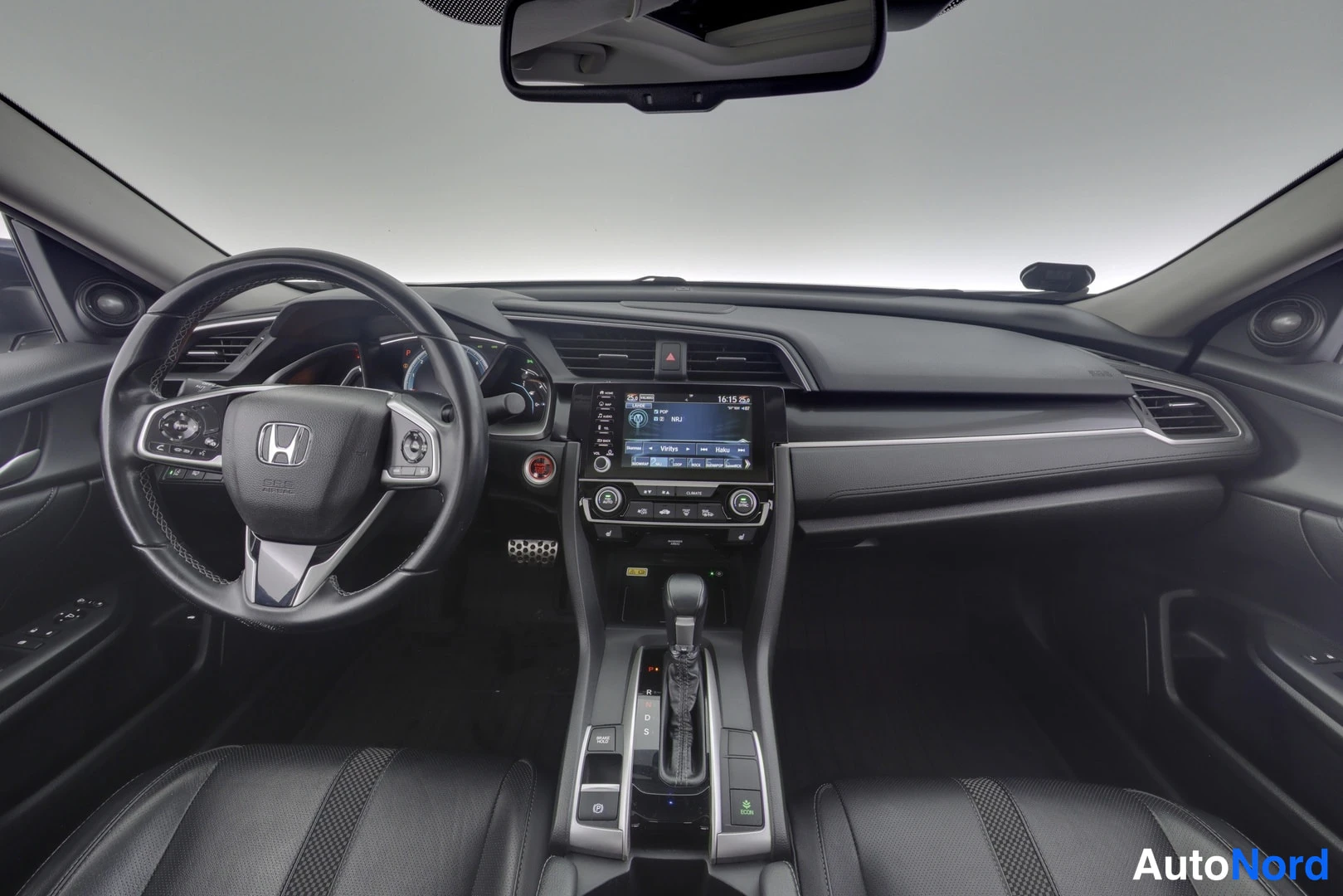 Yksityiskohta: Honda Civicin ohjaamo edestäpäin: musta nahkainen ohjauspyörä Honda-merkillä, kosketusnäytöllinen radio, automaattivaihteija ja kaksi etuistuinta.
