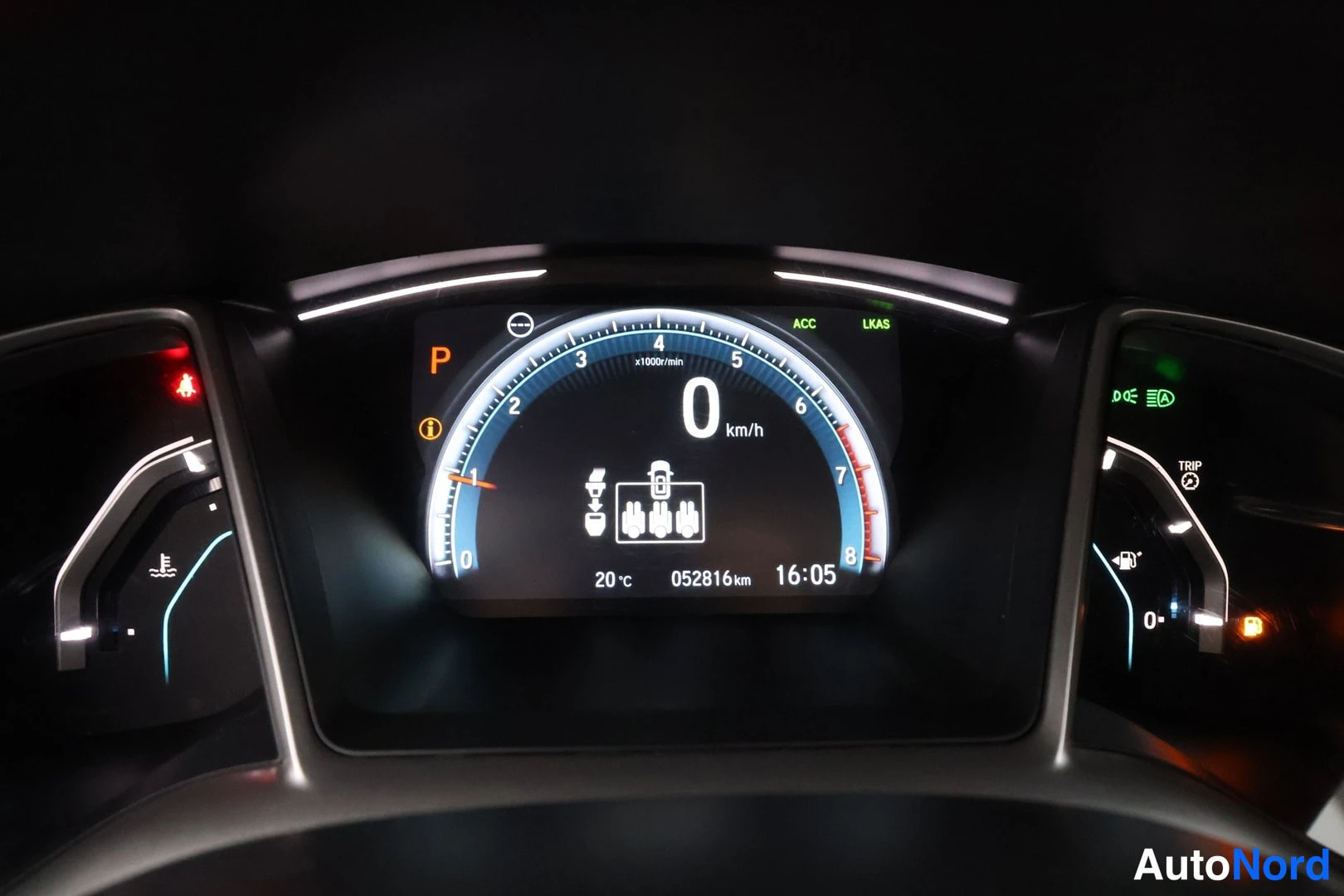 Yksityiskohta: Honda Civicin mittariston lähikuva: nopeusmittari 0 km/h, kirjain P, lukemat 20 °C, 052816 km ja 16:05, ACC- ja LKAS-merkitvalot.