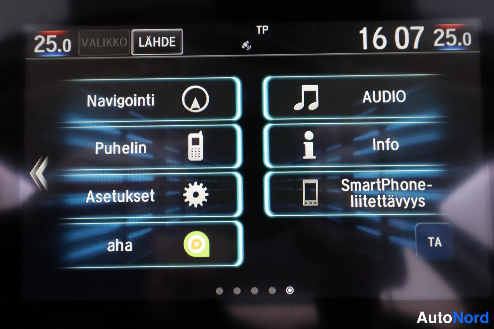 Muu: Auton infotainment-näytön valikko suomeksi: Navigointi, Puhelin, Asetukset, aha, Audio, Info ja SmartPhone-liitettävyys.
