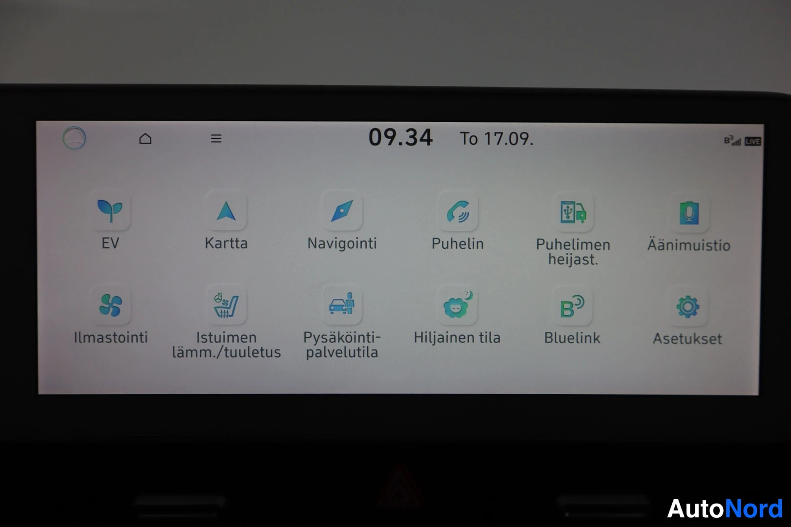 Yksityiskohta: Auton infotainment-näytön päävalikko suomenkielisillä sovelluskuvakkeilla, kello 09.34.