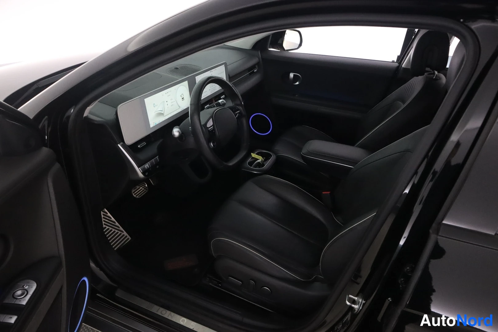Muu: Hyundai Ioniq 5:n etuistuin ja kojelauta avatusta kuljettajan ovesta katsottuna.