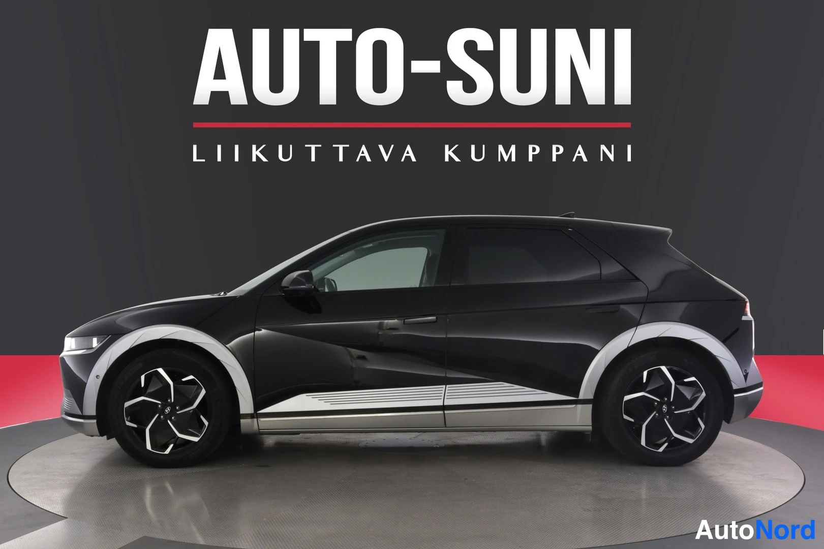 Sivulta: Hyundai IONIQ 5:n sivuprofiili studiossa, auton kylki ja pyörät näkyvät tummaa taustaa vasten.