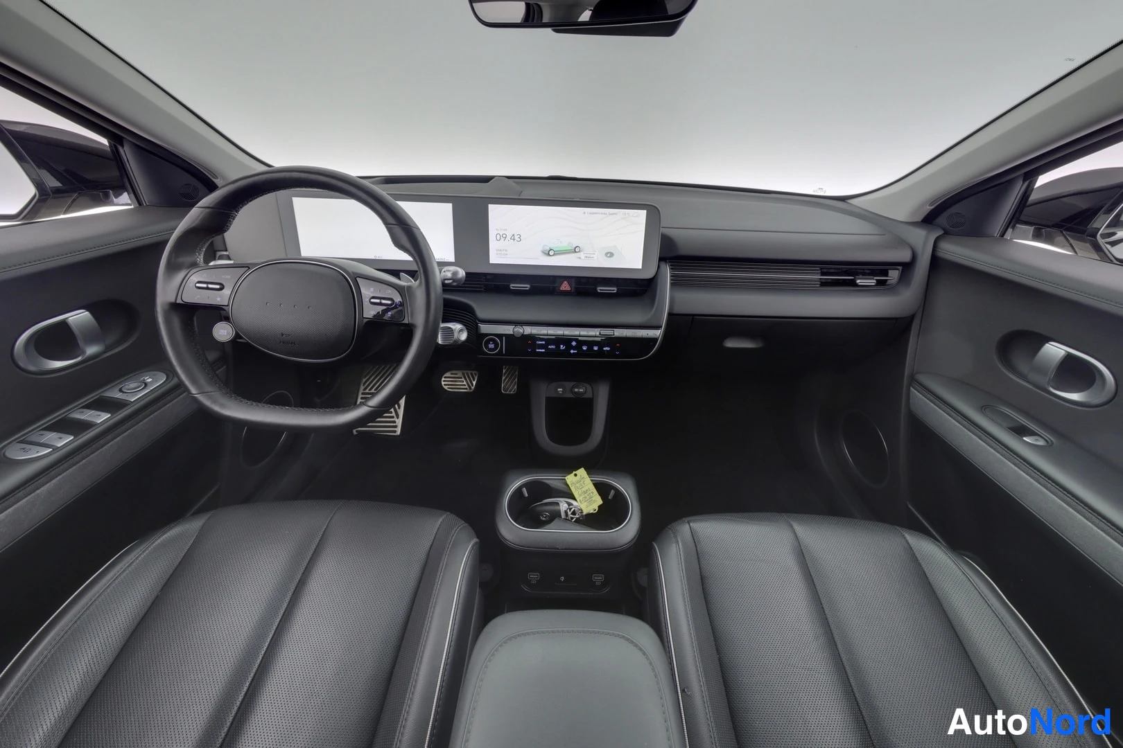 Yksityiskohta: Hyundai IONIQ 5:n etusisätilan ohjaamo: ohjauspyörä, mittaripaneelin näytöt, keskikonsoli ja kaksi etuistuinta.