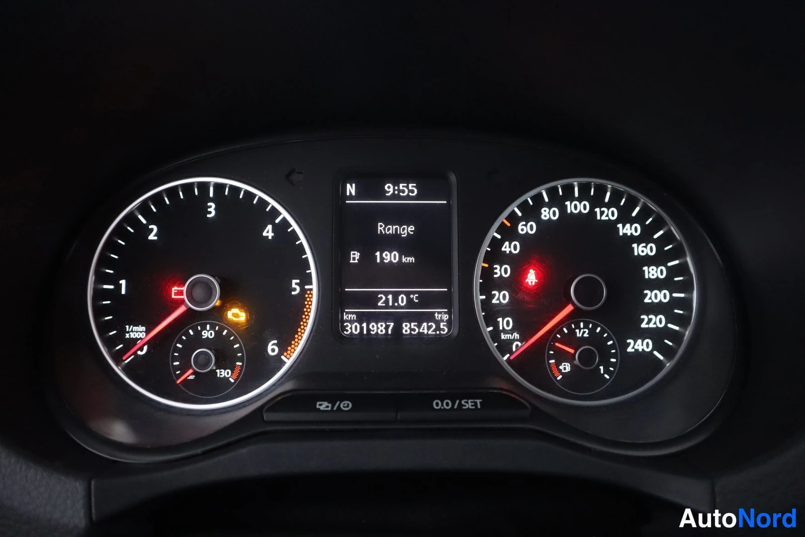 Etuviisto: Kojelaudan mittaristo lähikuvassa: kierrosmittari (1/min x1000) vasemmalla, nopeusmittari 240 km/h asti oikealla ja keskellä näyttö, jossa tekstit N, 9:55, Rang