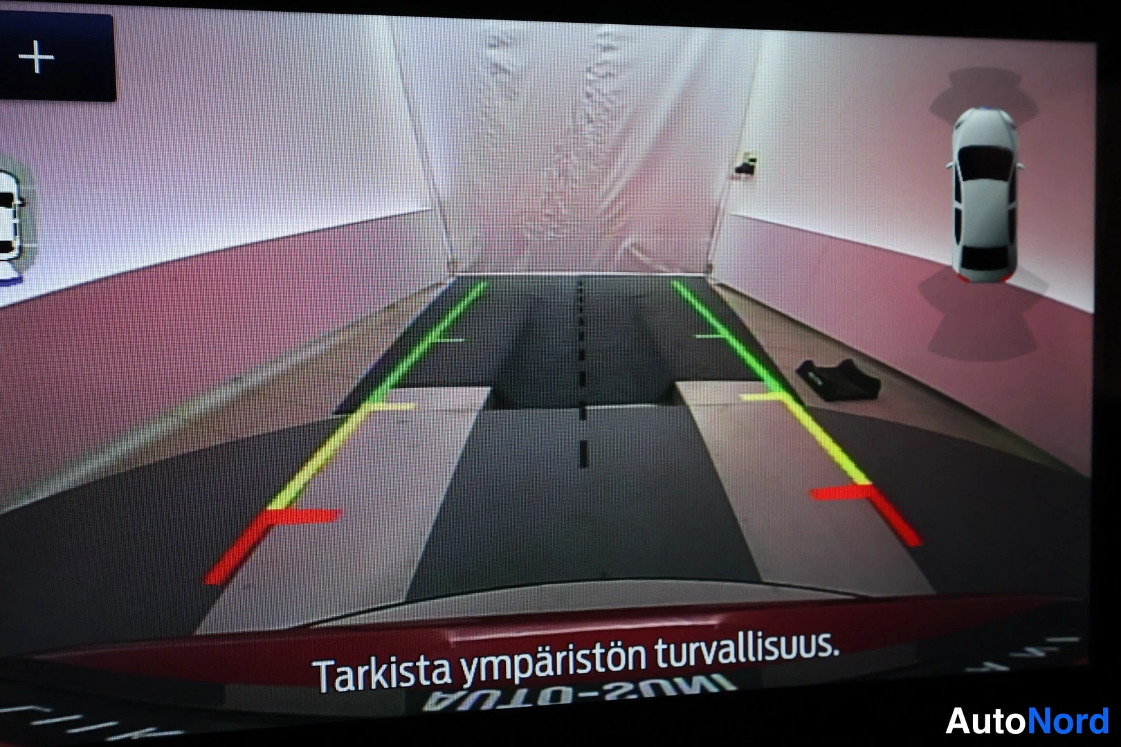 Muu: Näyttö, jossa näkyy auton takakameran kuva ohjeviivoineen ja teksti: Tarkista ympäristön turvallisuus.