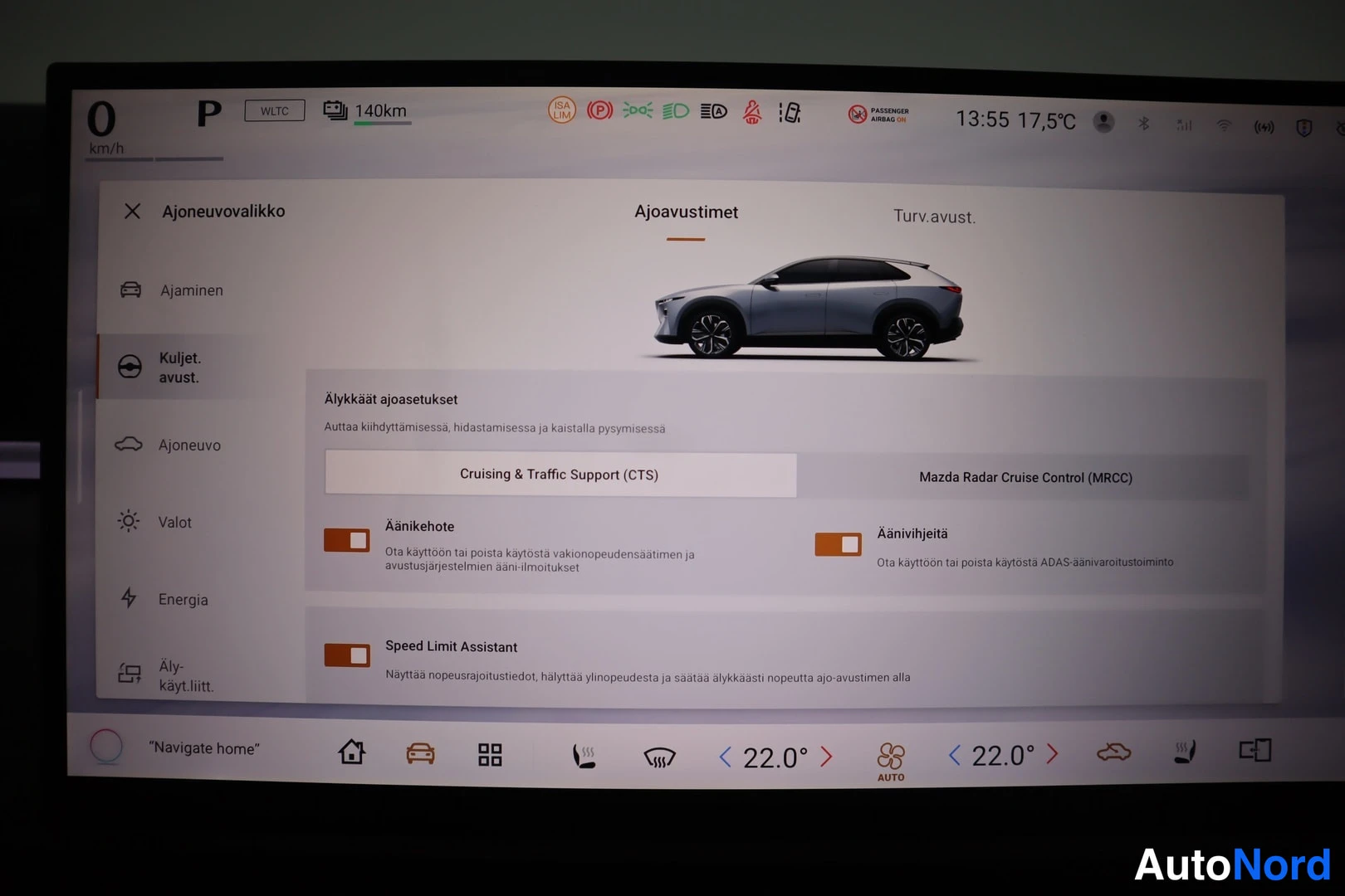 Yksityiskohta: Auton kojelaudan suuri infotainment-näyttö, jossa näkyy ajoavustimet-valikko ja asetuskytkimiä.