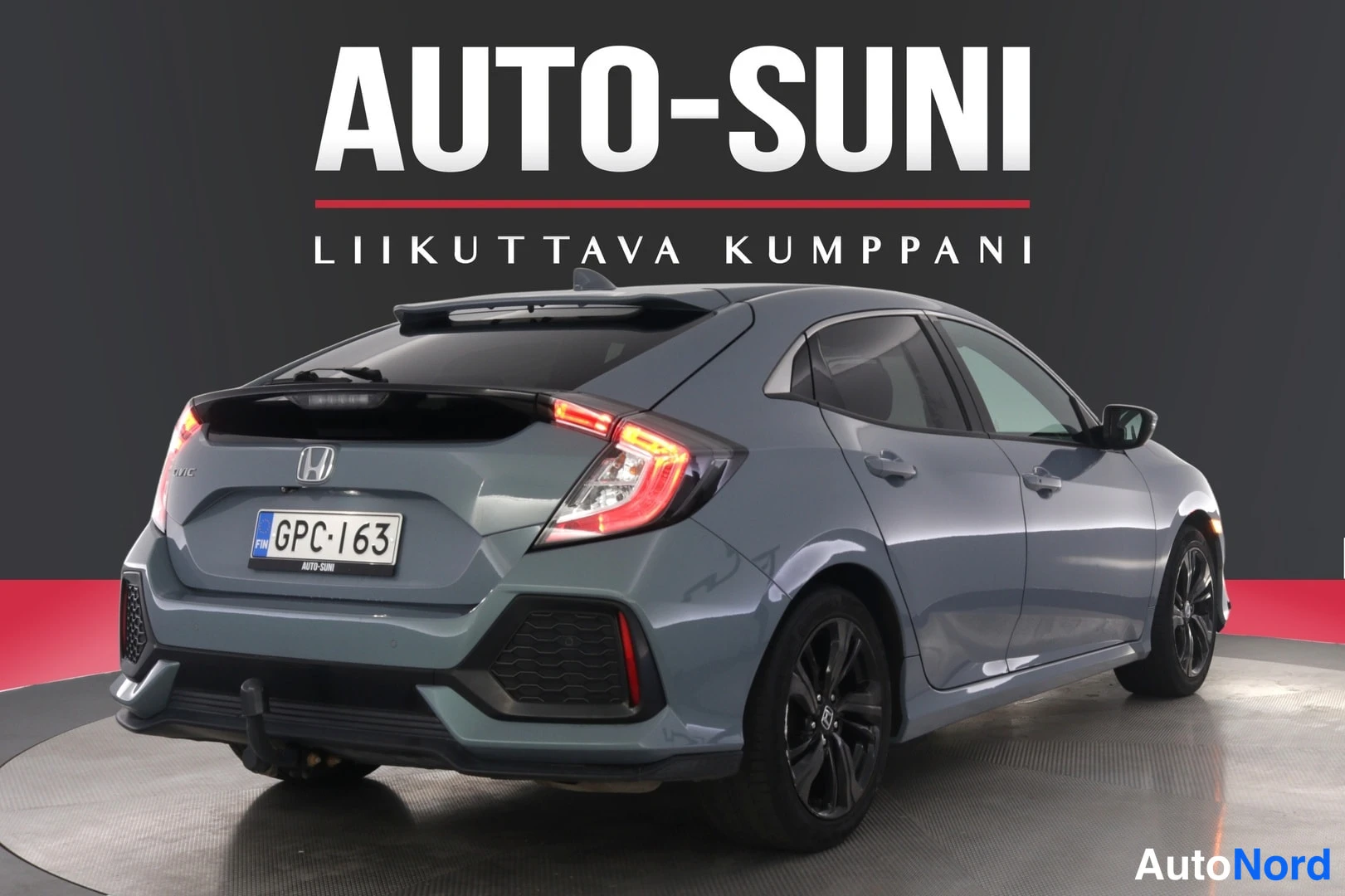 Takaviisto: Harmaansinisen Honda Civicin takakulmanäkymä; rekisterikilpi ja punaisina hohtavat takavalot ovat näkyvissä.