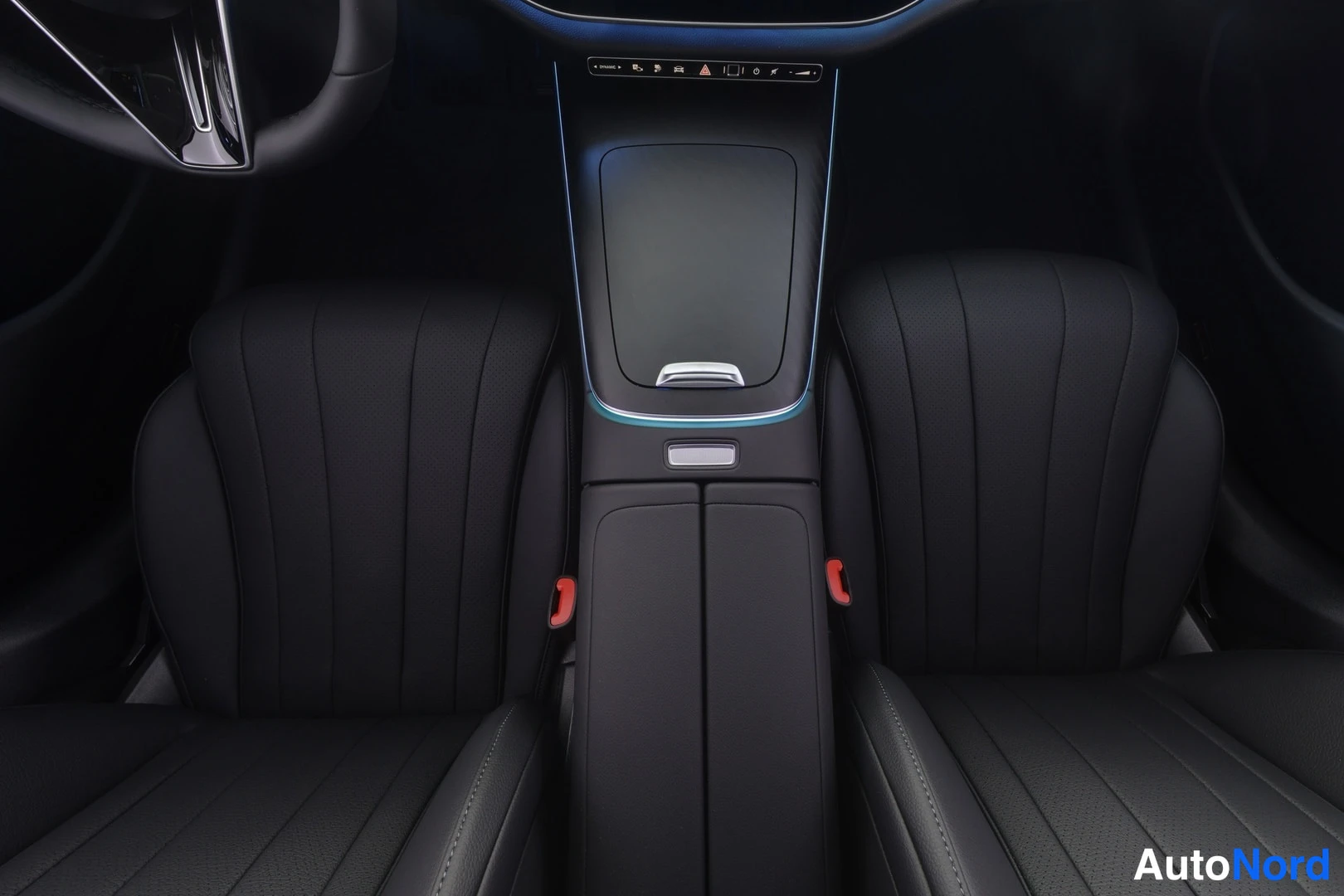 Sivulta: Mercedes-Benz center console between two black leather front seats with MBUX touchscreen visible, dark cabin lighting