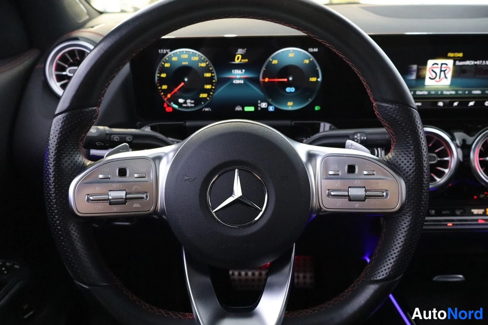 Sivulta: Mercedes-tähdellä varustettu musta nahkainen ohjauspyörä ja täysdigitaalinen mittaristo, jonka nopeusnäyttö näyttää 0 km/h ja matkatieto 1184,7 km / 42846 km.