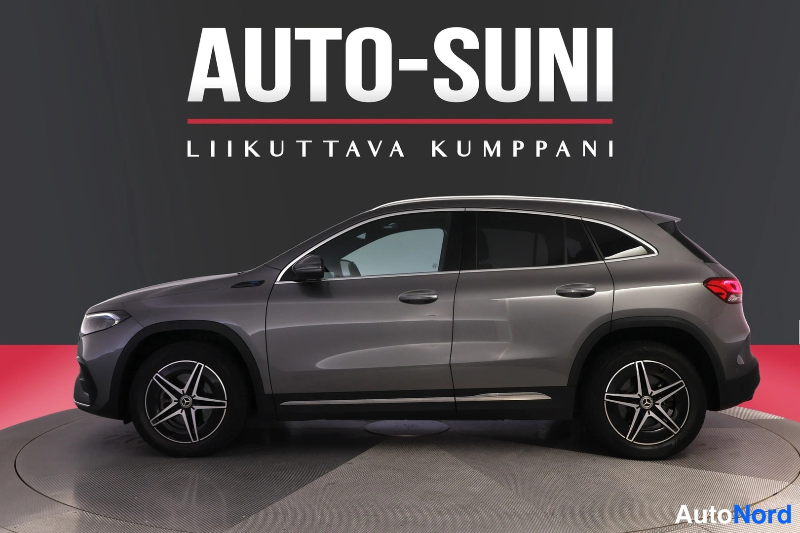 Sivulta: Mercedes-Benz EQA:n sivuprofiili, harmaa korimatala studiovalaistuksessa punaisella taustalla.
