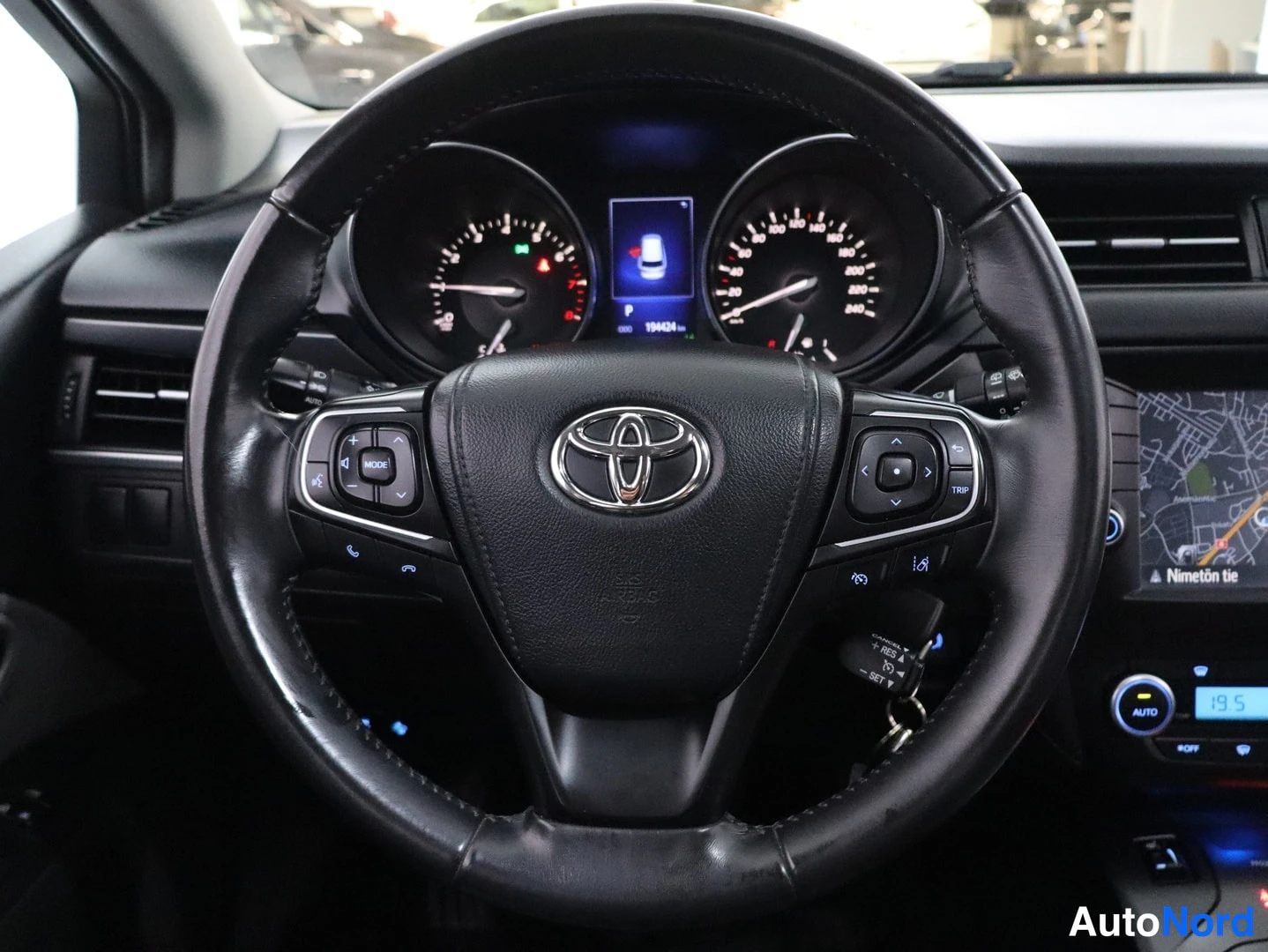 Etuviisto: Steering wheel with center Toyota badge, dashboard instruments visible behind