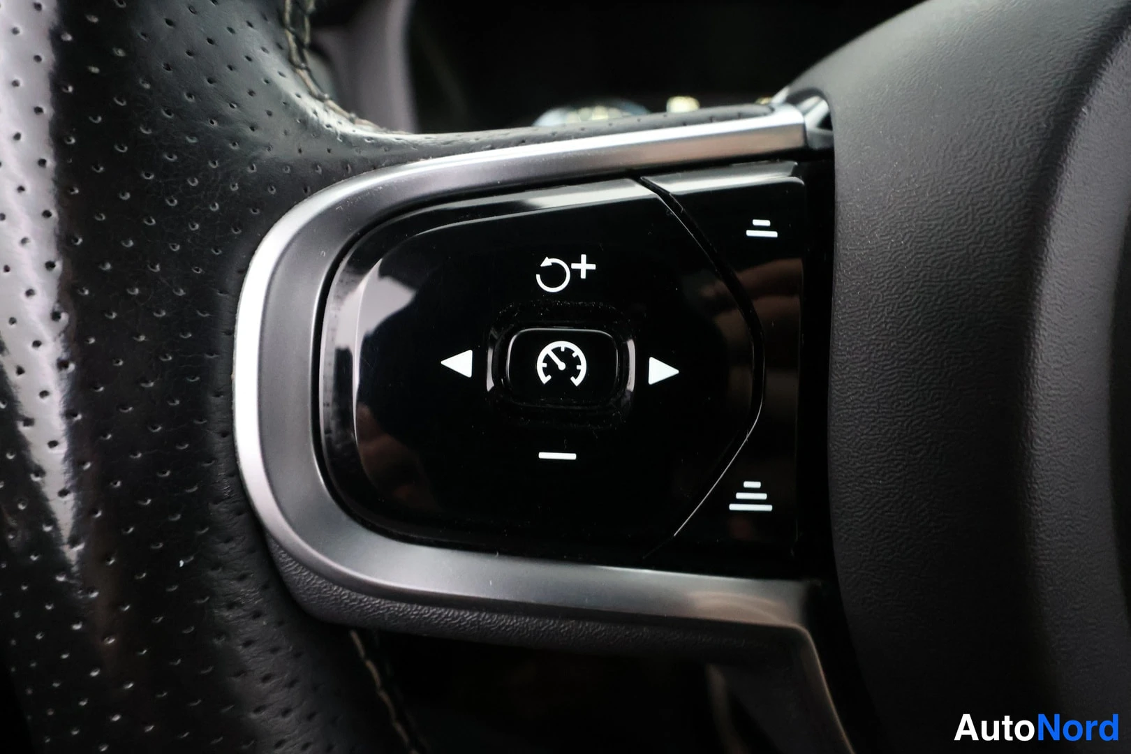 Muu: Ohjauspyörän oikeanpuoleinen nappiryhmä lähikuva: cruise control - ja nopeudensäätösymbolit, nappiryhmän ympärillä lämmittelevä aukollinen nahkainen ohjauspyörä