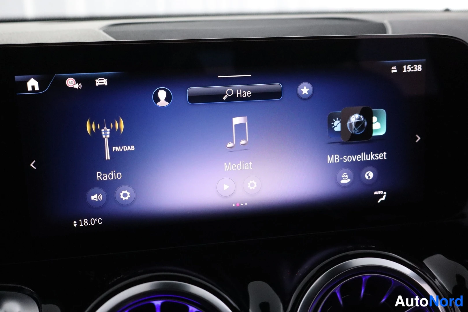 Muu: Kojetaulun infotainment-näytön lähikuva: valikot Radio, Mediat ja MB-sovellukset, FM/DAB-merkintä sekä 18,0 °C lämpötieto.