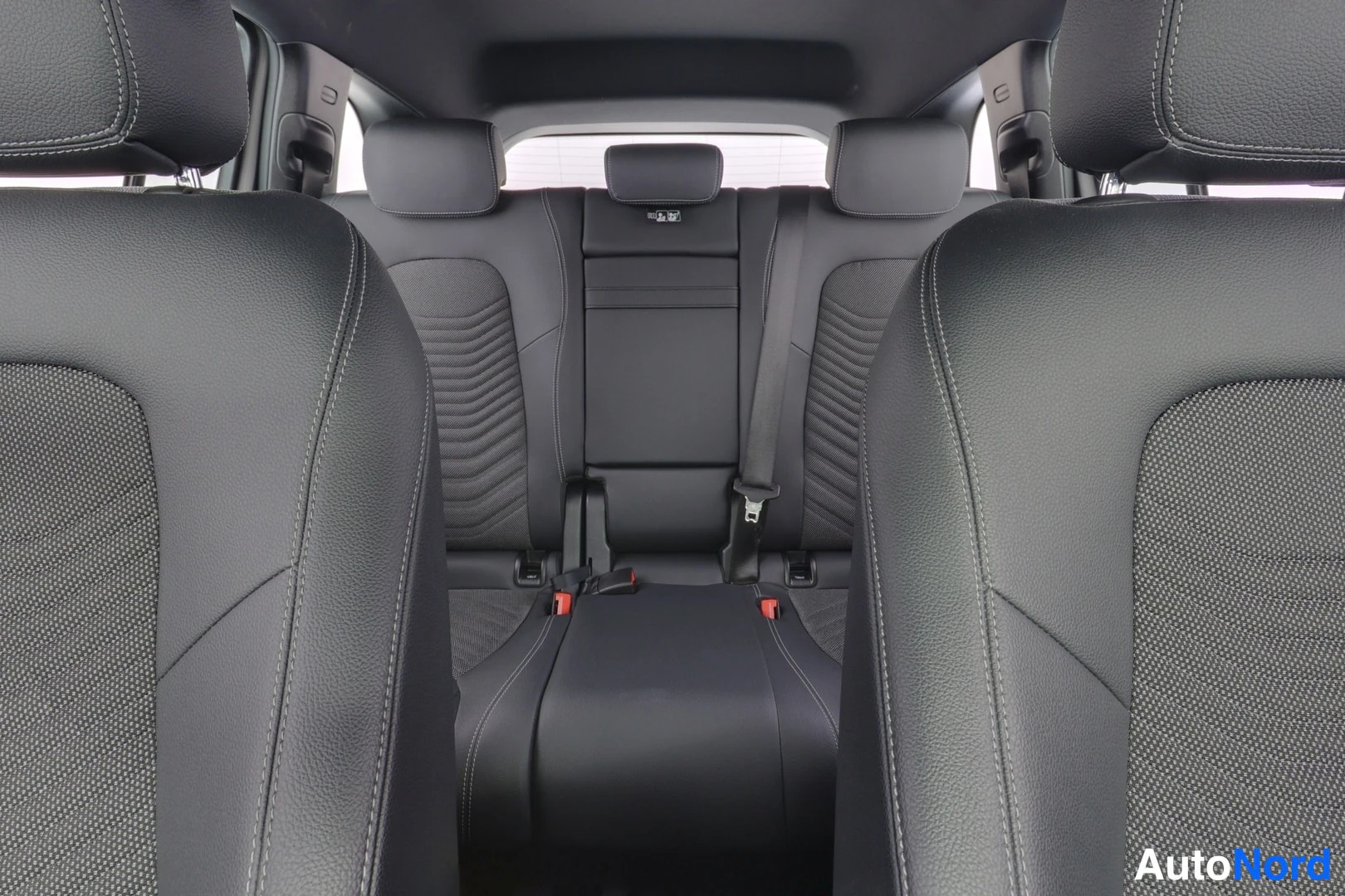 Takaistuimet: Rear cabin view from behind front seats showing three headrests on the back seat bench and seatbelt anchors.