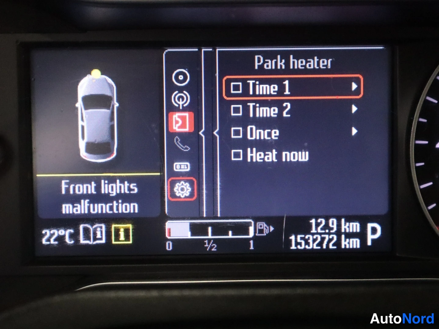 Edestä: Kojelaudan infotainment-näyttö lähikuvassa, jossa näkyy 'Front lights malfunction' -varoitus ja 'Park heater' -valikko Time 1-, Time 2-, Once- ja Heat now -vaih